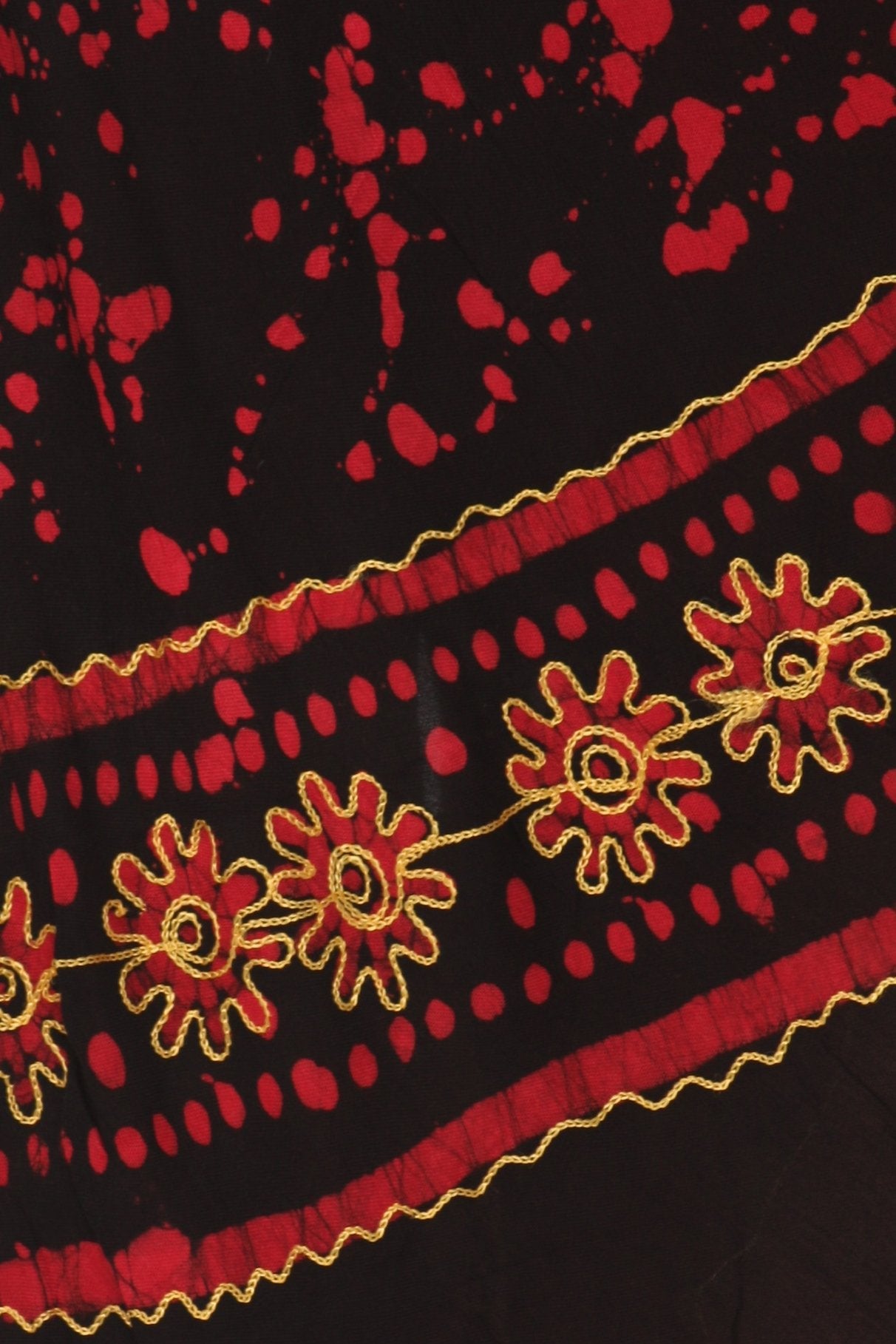 Close-up of a black fabric with red floral embroidery and gold trim.