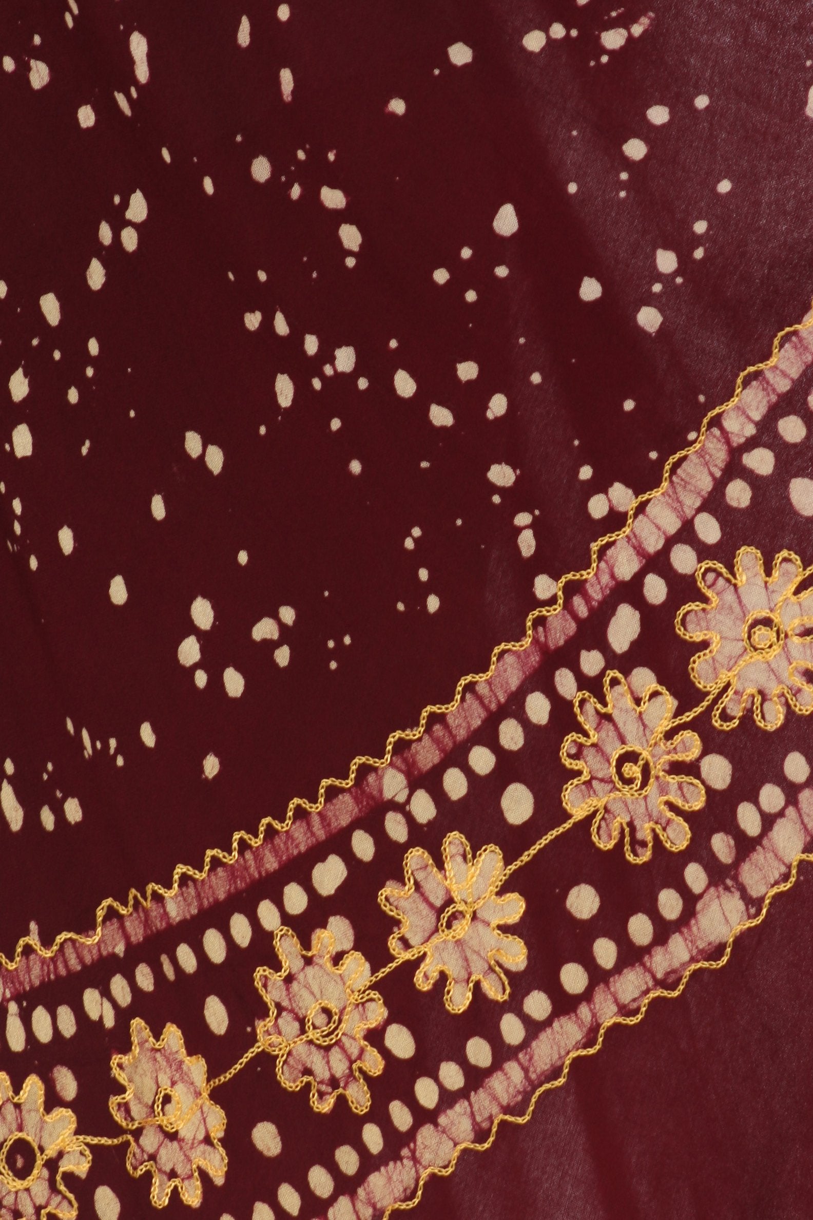 Close-up of a maroon fabric with gold floral embroidery