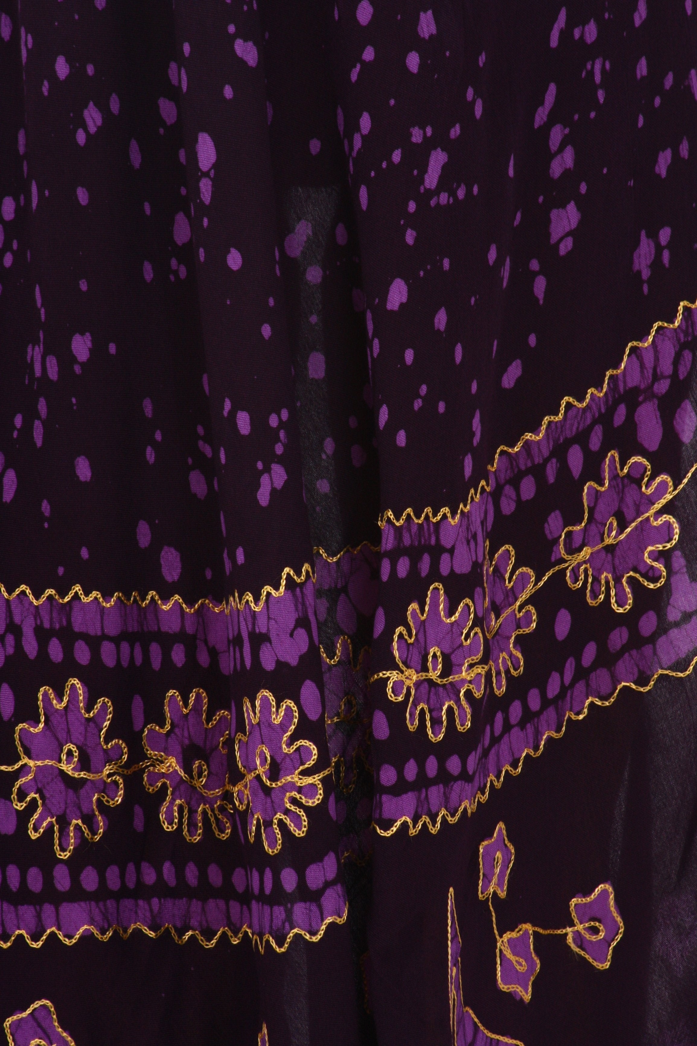 Close-up of a purple fabric with gold embroidery on a dark background