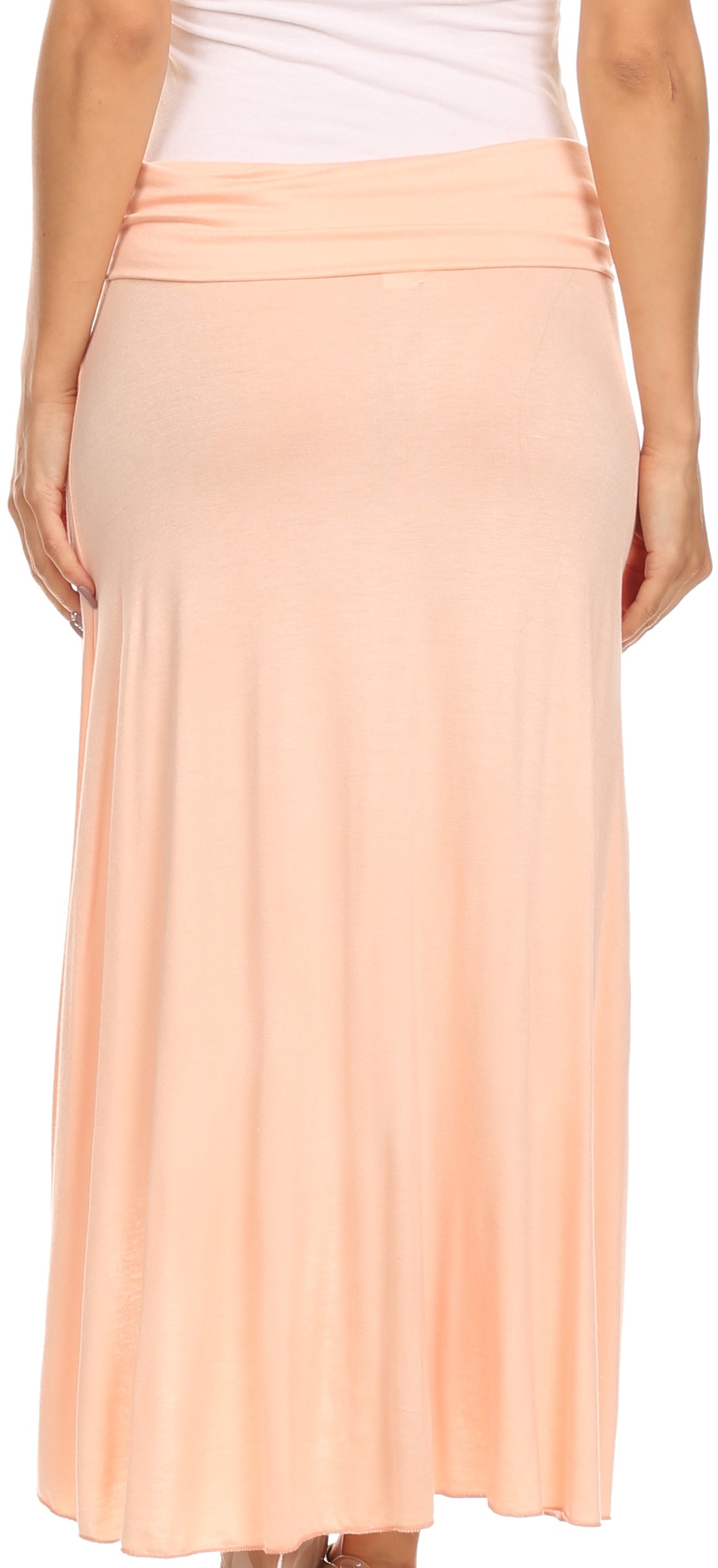 Woman wearing a peach skirt with a white top on a plain background