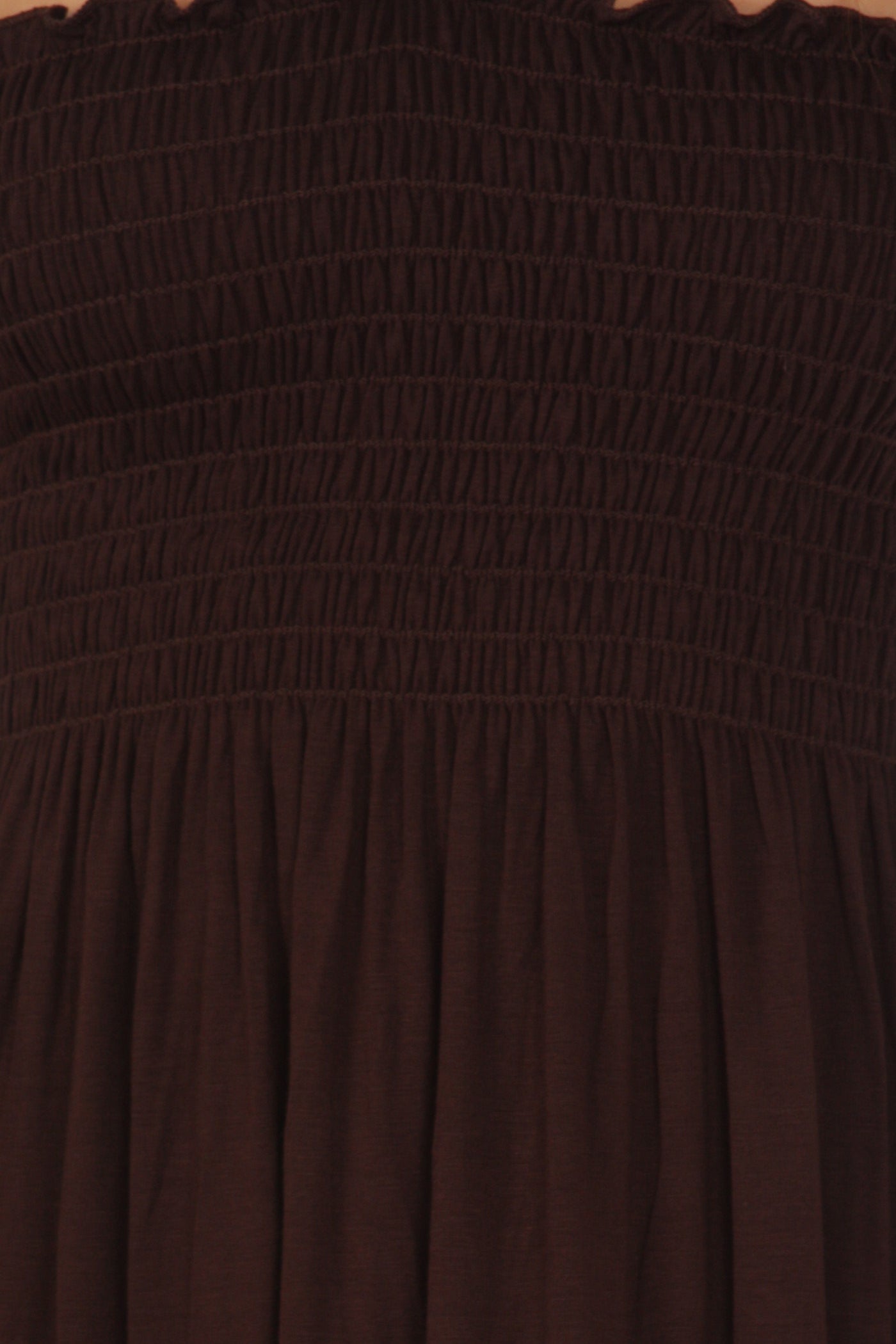 Close-up of a brown strapless dress with smocked bodice