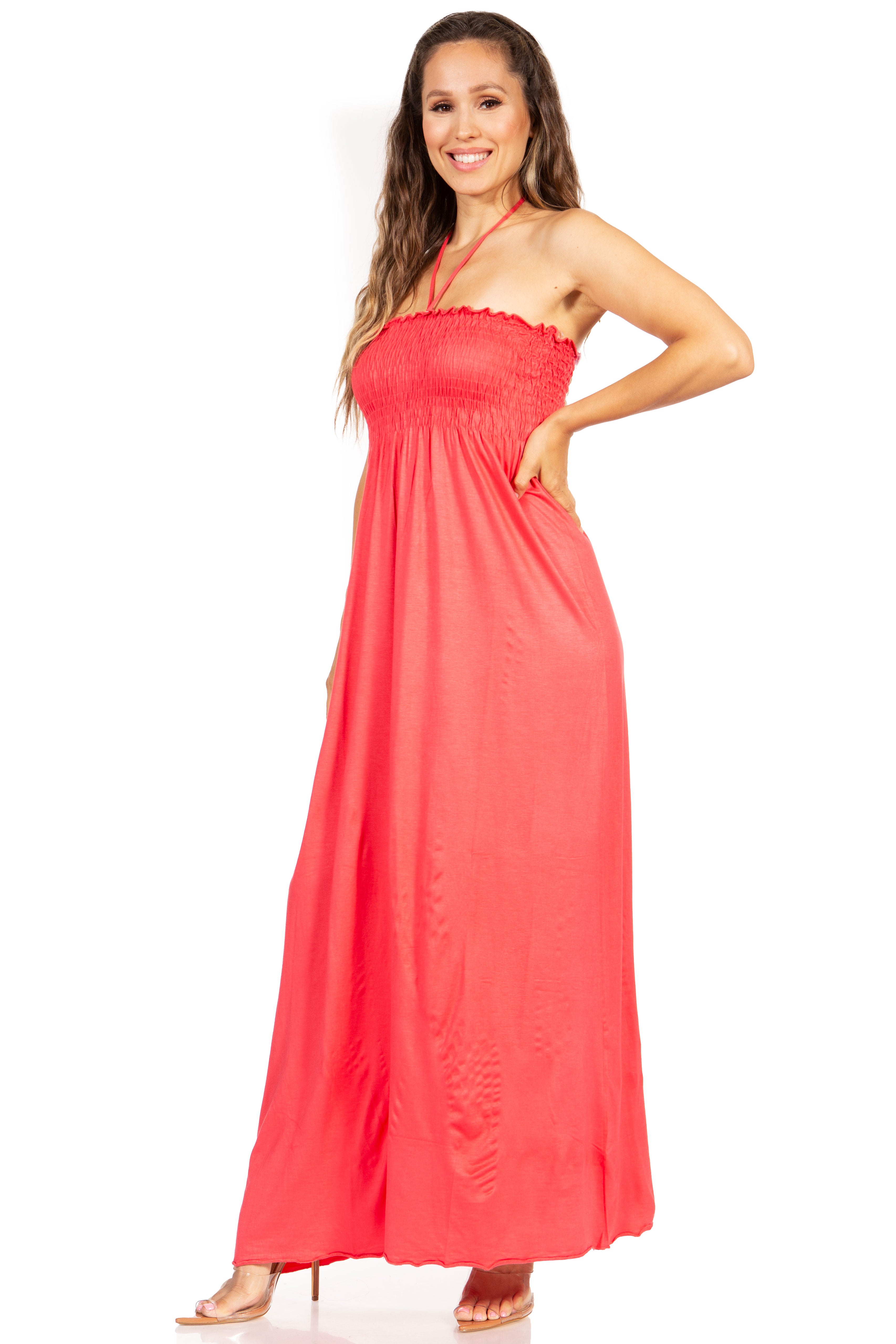 Woman wearing a coral halter neck maxi dress on a white background