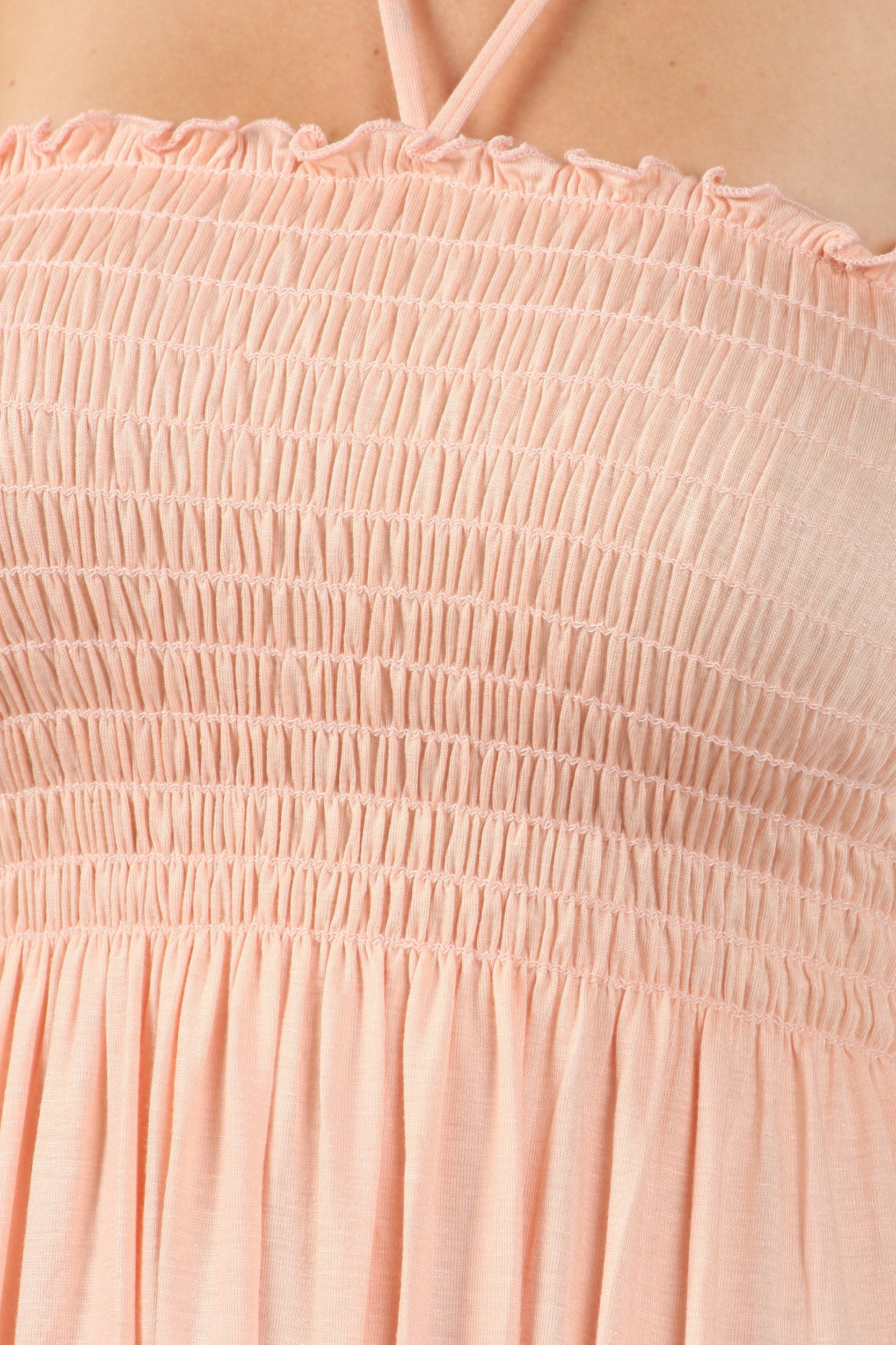 Close-up of a pink smocked dress with thin straps.