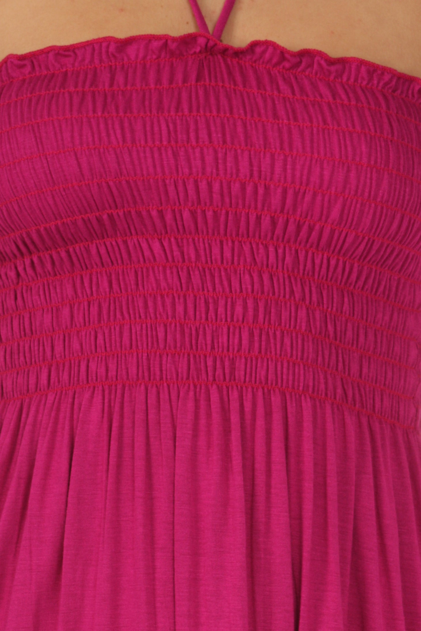Close-up of a pink dress with smocked bodice on a beige background