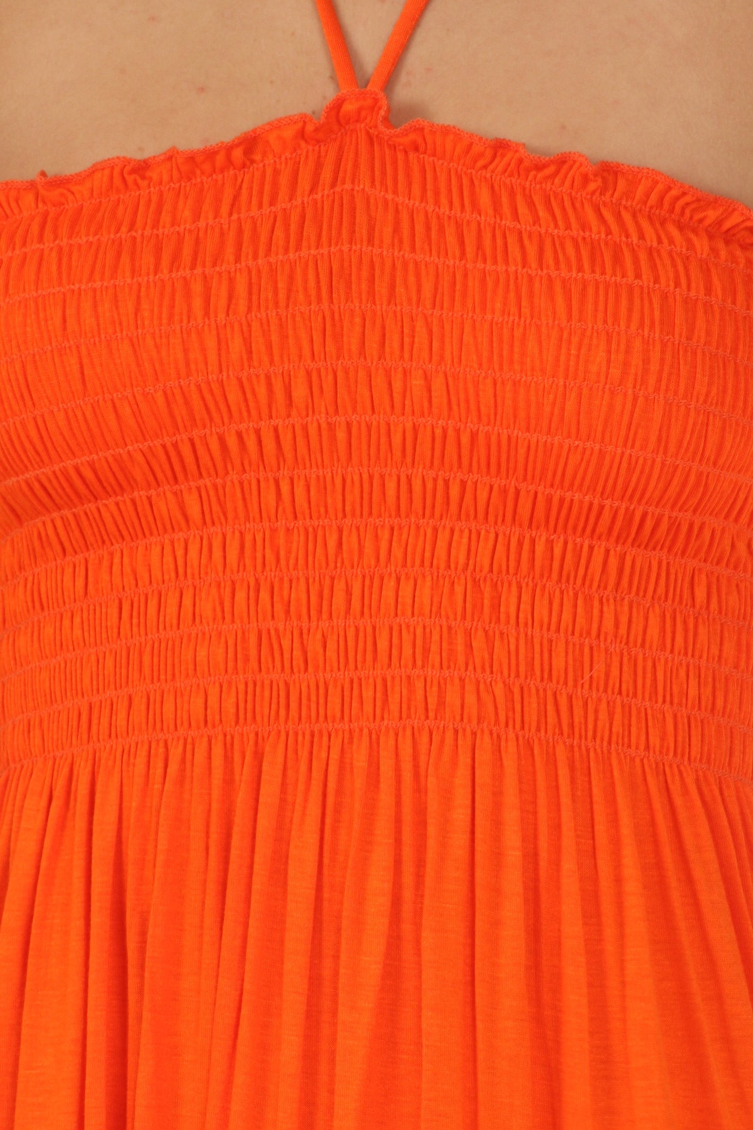 Close-up of an orange dress with smocked bodice on a beige background