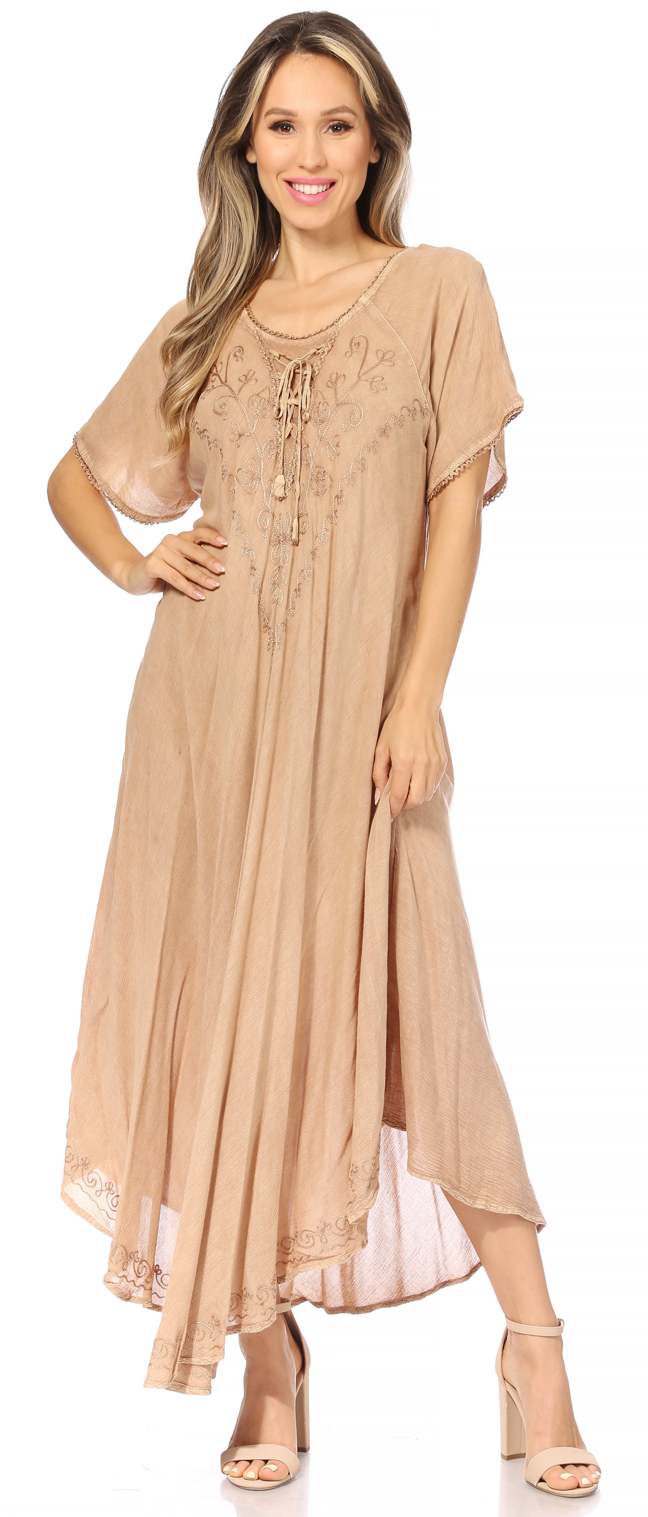Woman wearing a beige long dress with a white lace overlay on a white background