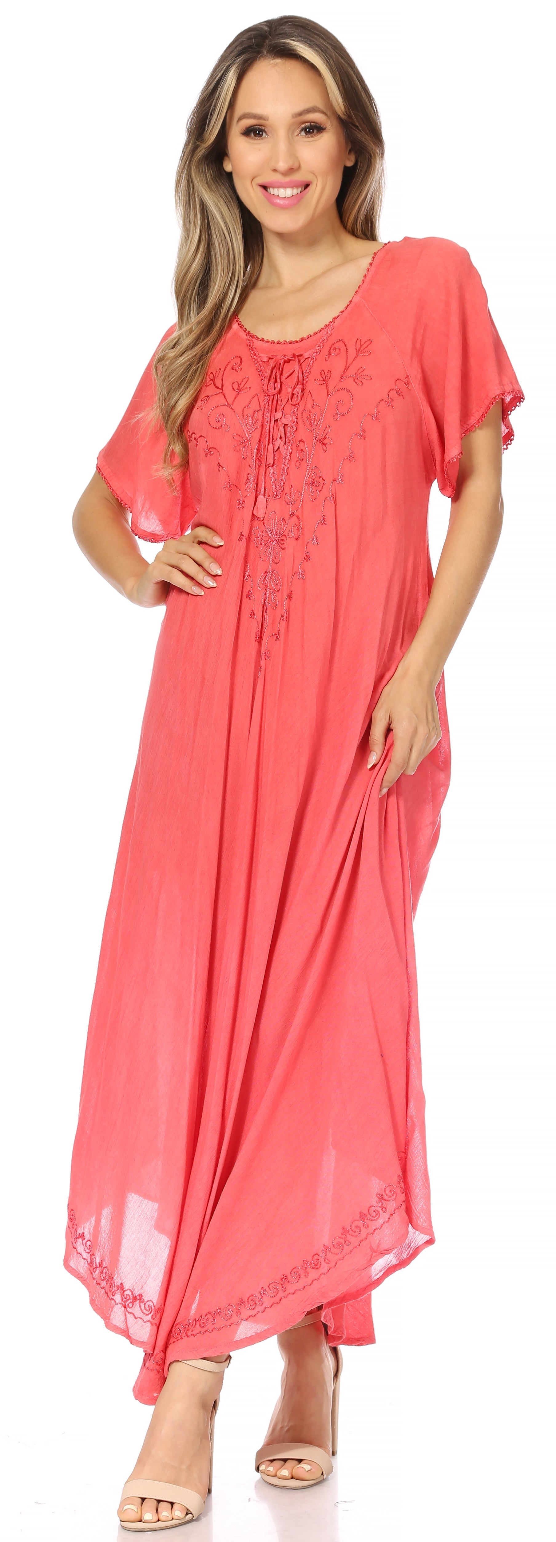 Woman wearing a coral pink dress with lace details on a white background