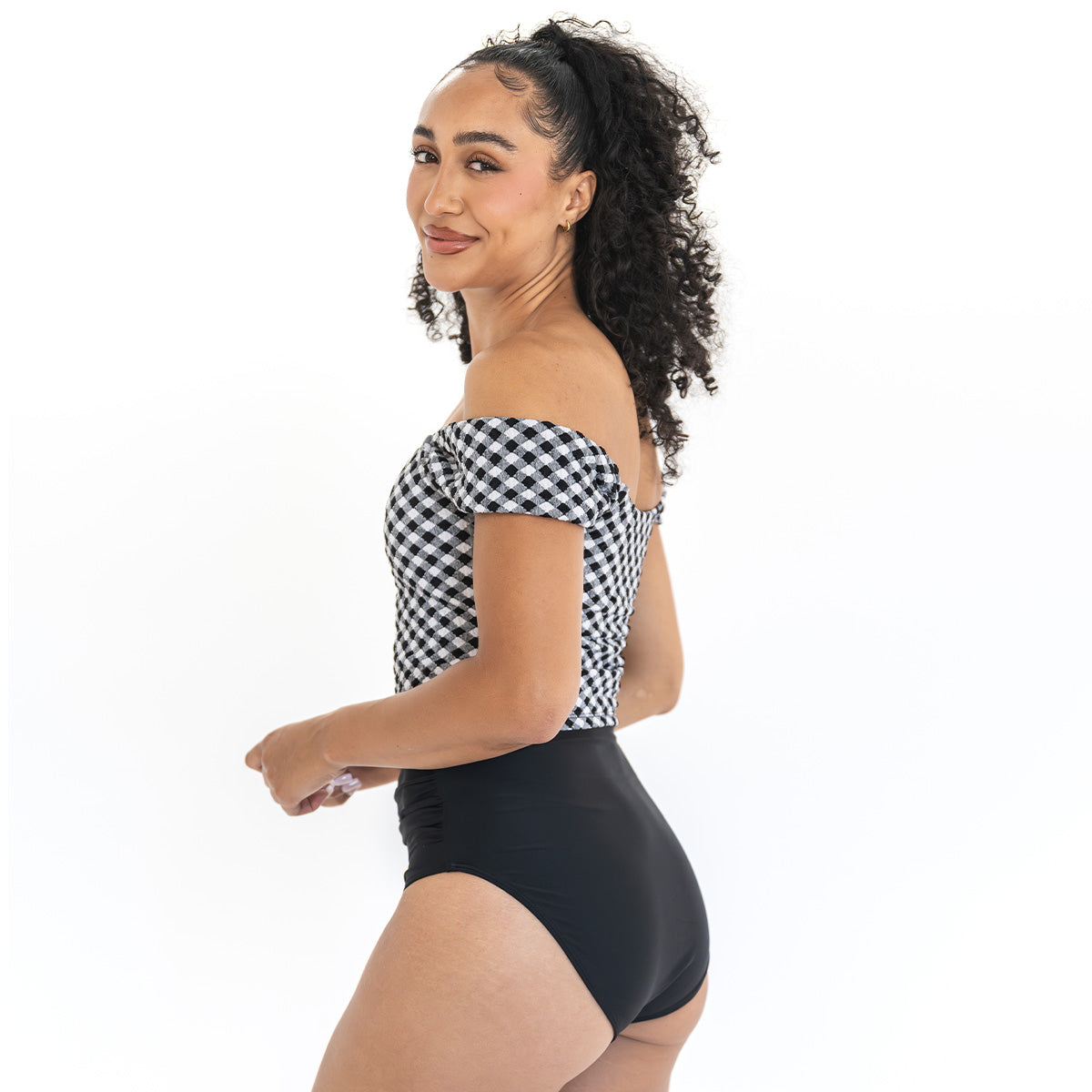 Woman wearing a black and white checkered top and black high-waisted bikini bottom on a white background