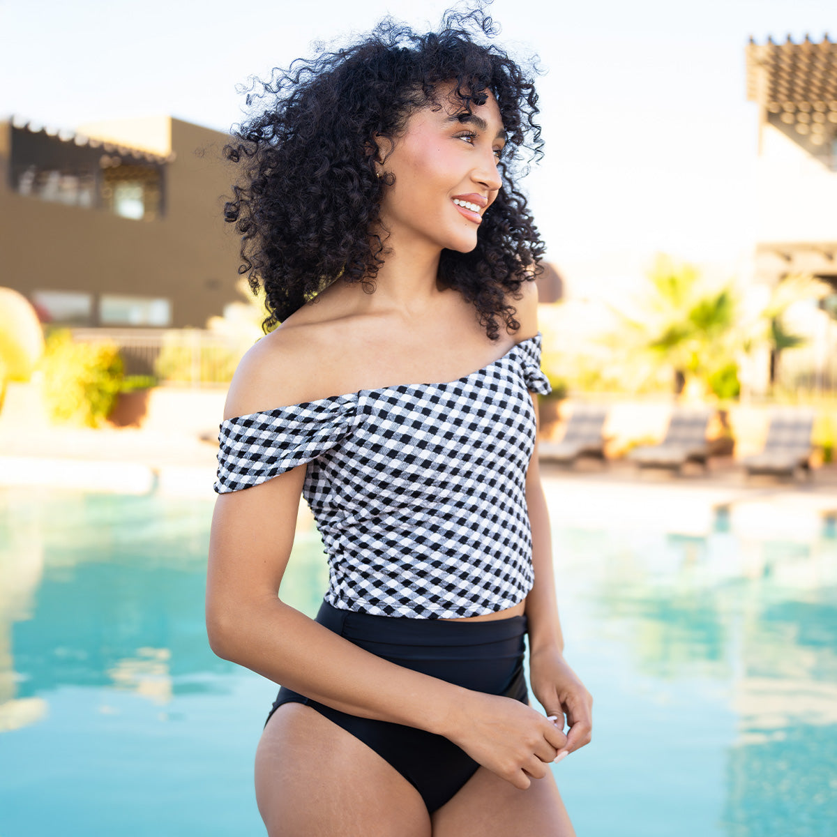 Woman in a checkered top and black bottoms by a pool