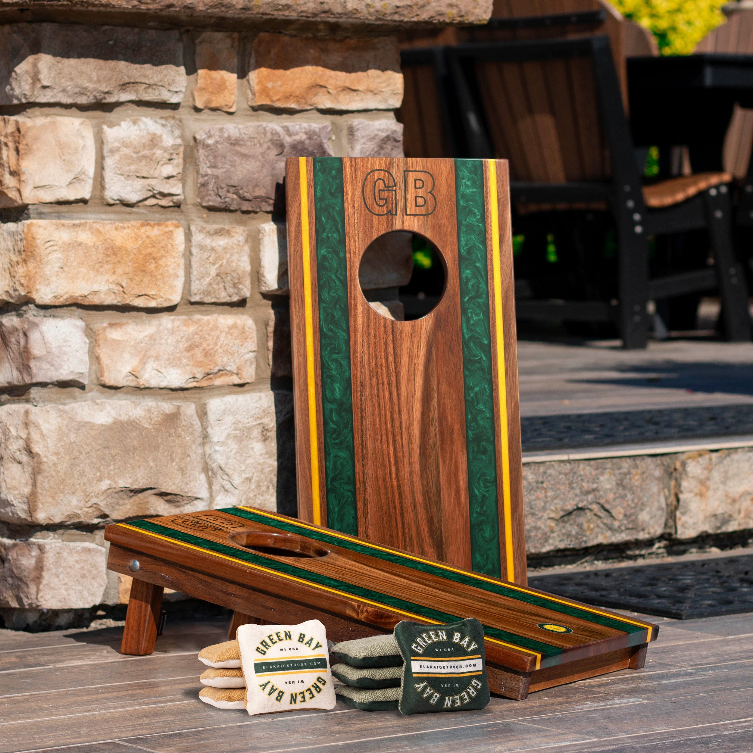 Wooden cornhole board with 'GB' branding on a stone patio