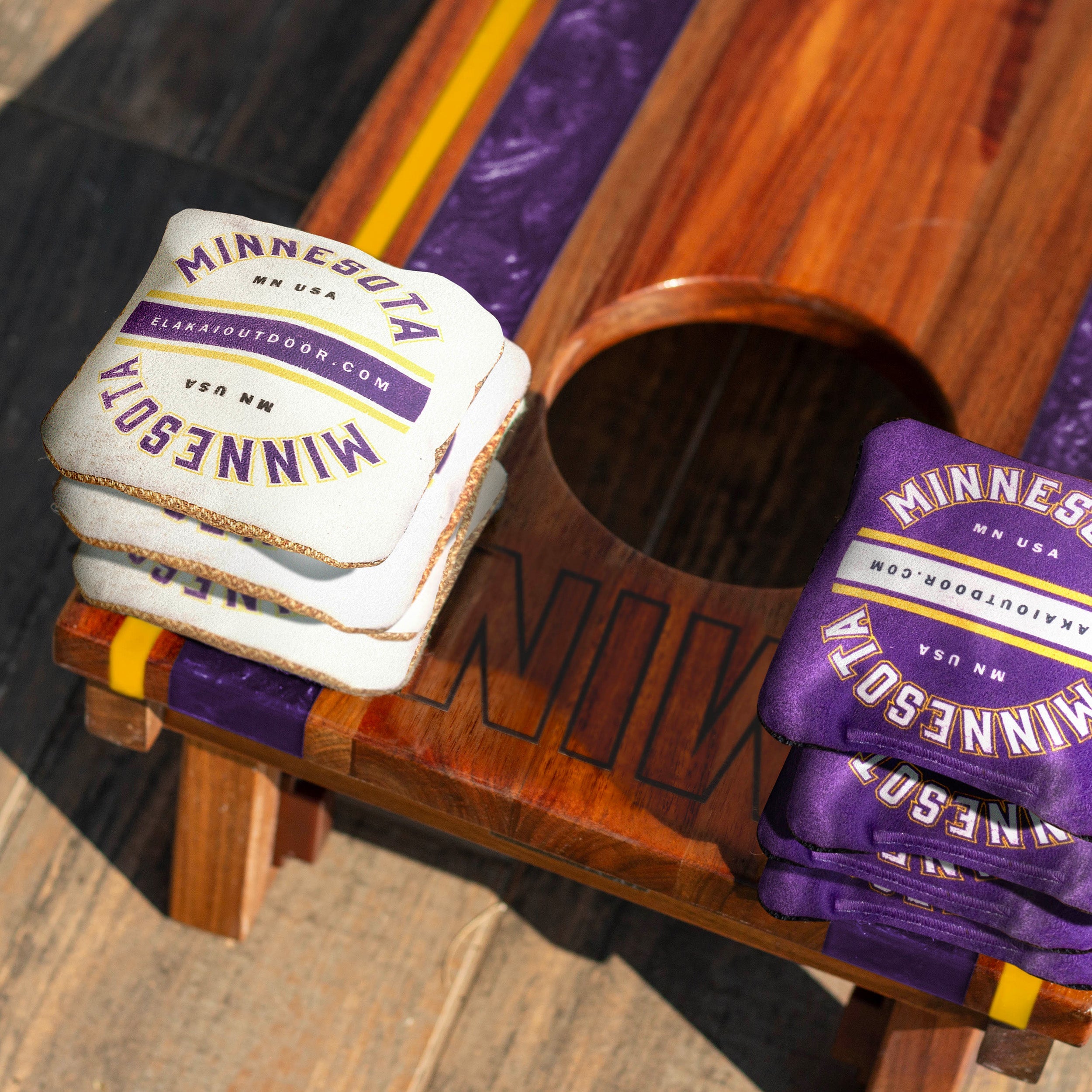 Stack of coasters and purple gloves with 'Minnesota' branding on a wooden surface.