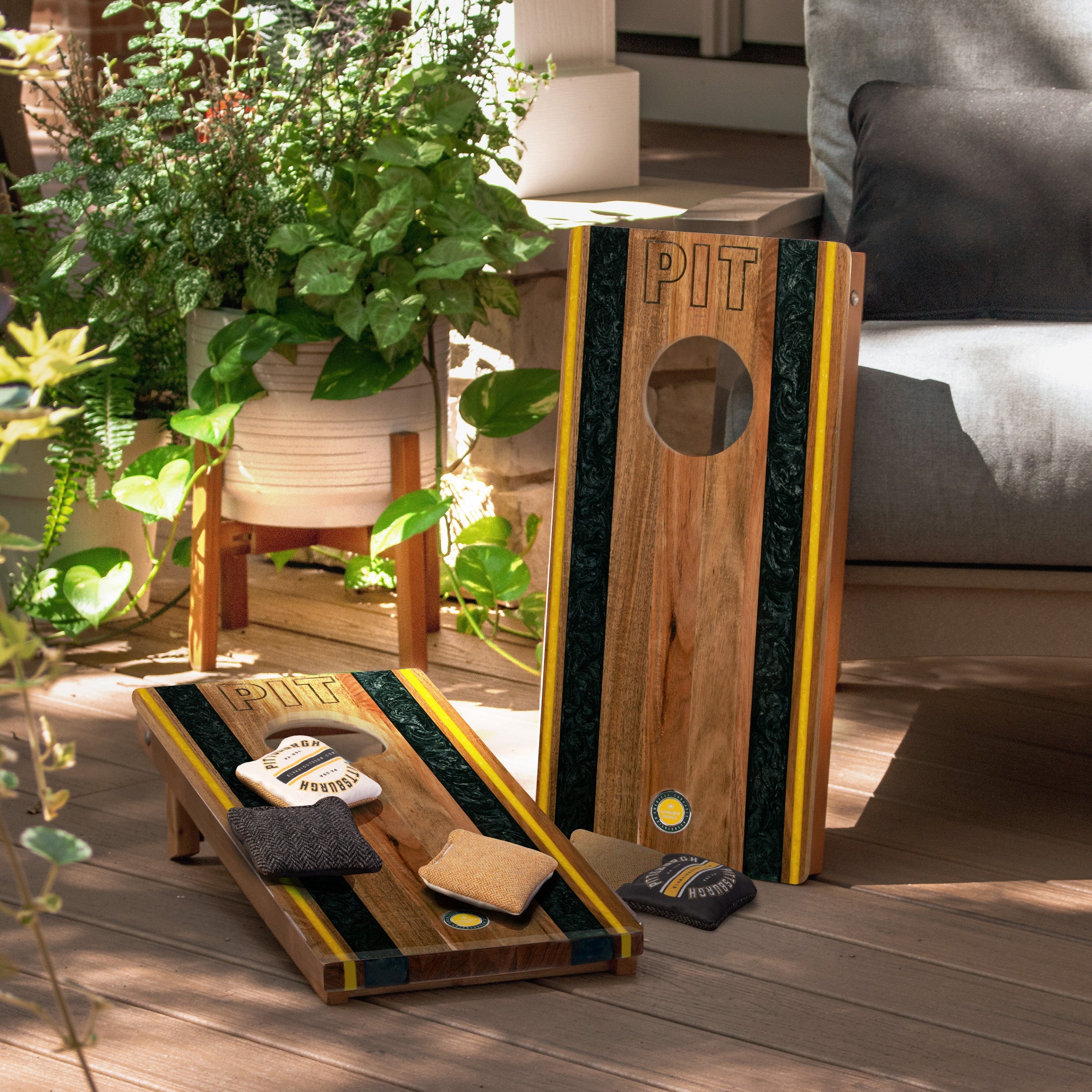 Wooden cornhole boards with 'PIT' branding on a wooden deck.