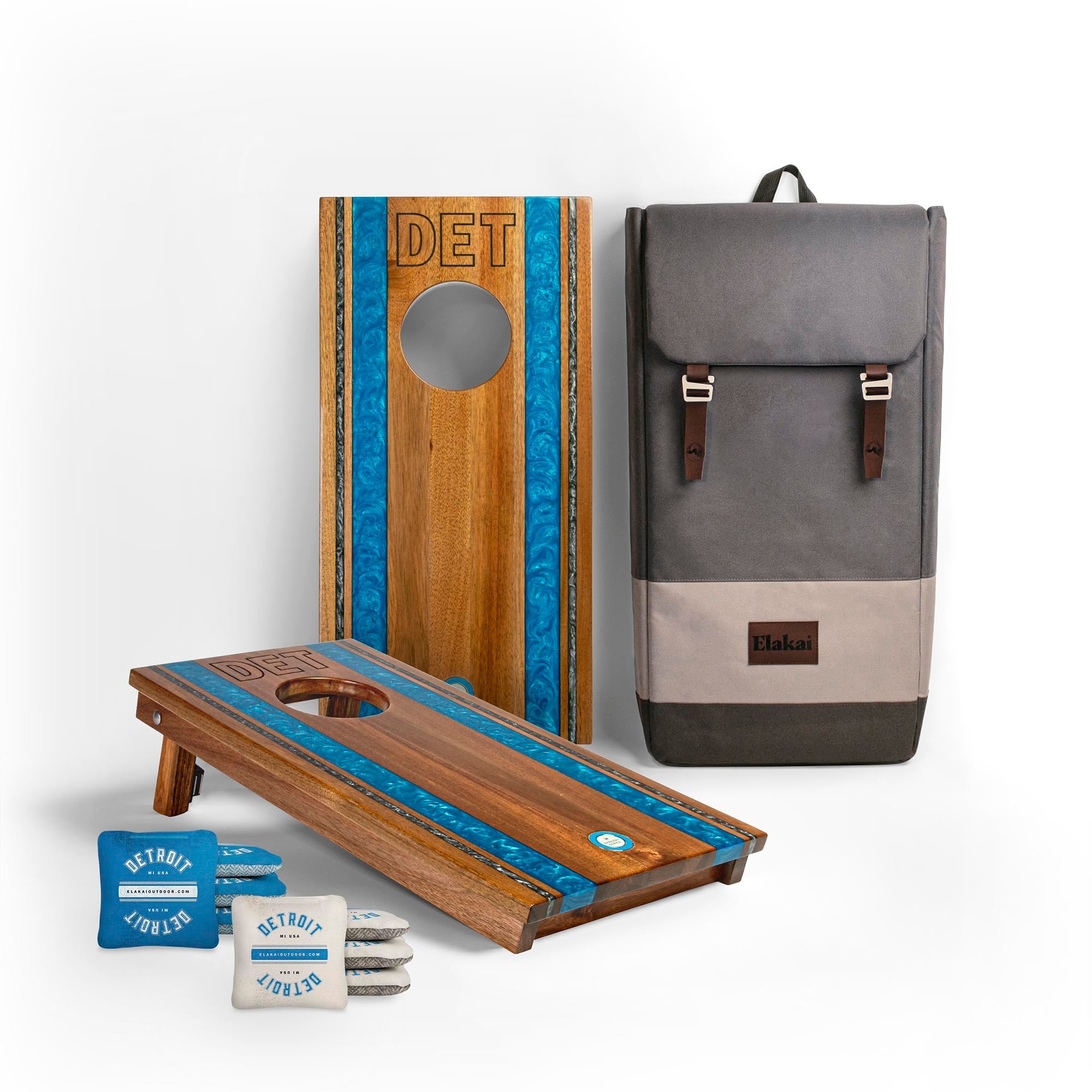 Wooden cornhole boards with blue accents, a gray backpack, and small bags on a white background.
