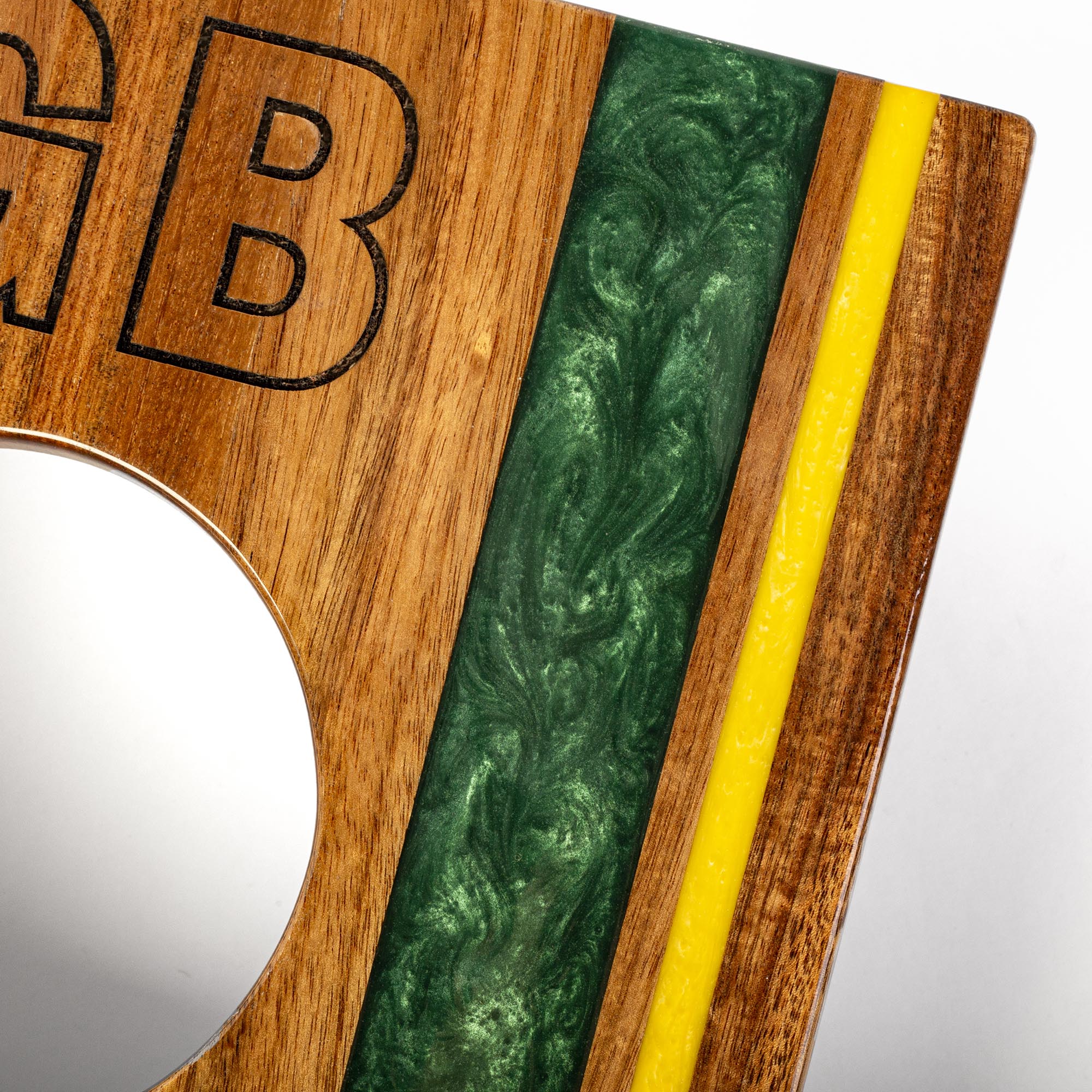 Wooden plaque with engraved letter 'B' and green and yellow marbled inlay on a white background