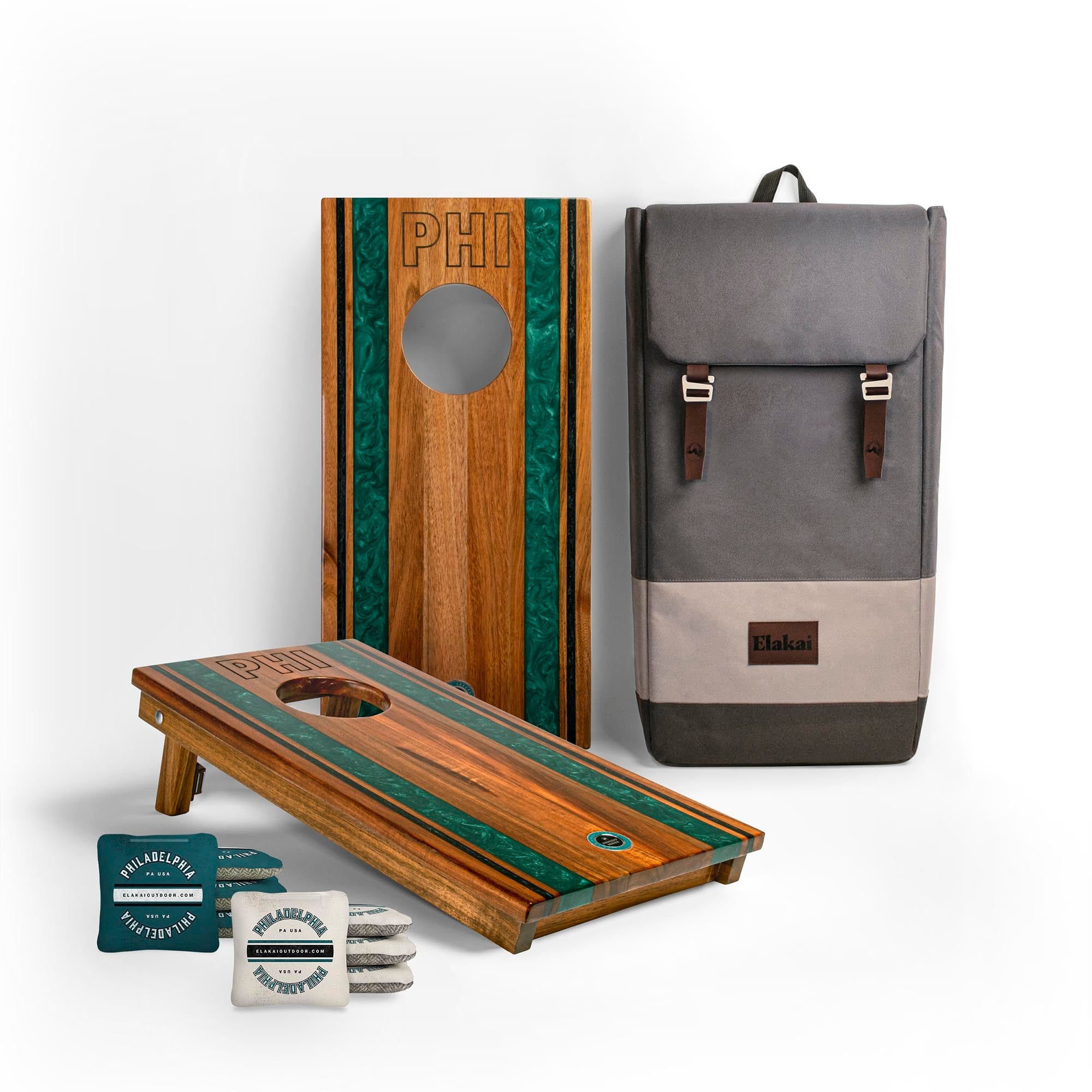 Two wooden cornhole boards with green stripes, a gray backpack, and a small container on a white background.