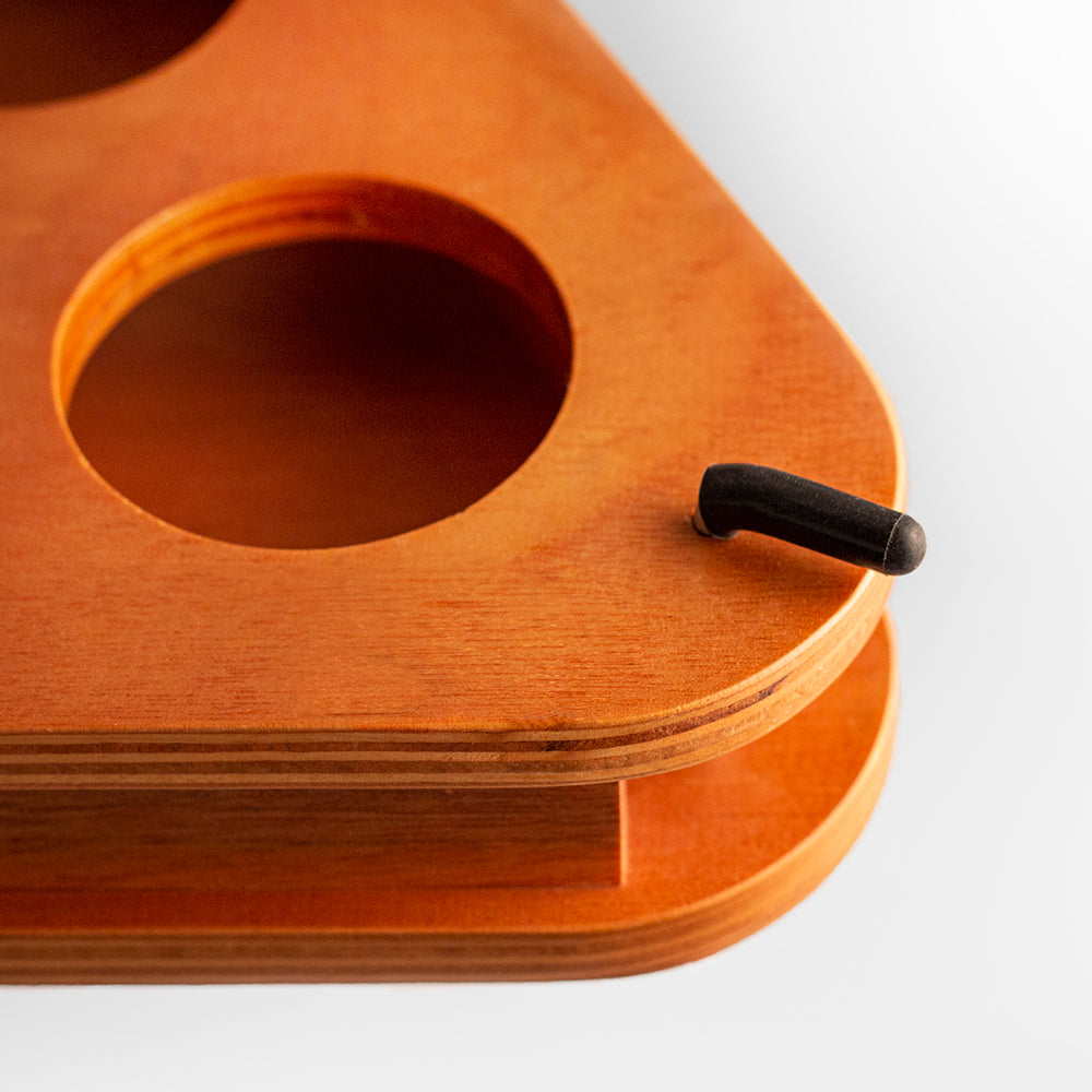 Wooden product with a central circular hole and a black handle on a white background