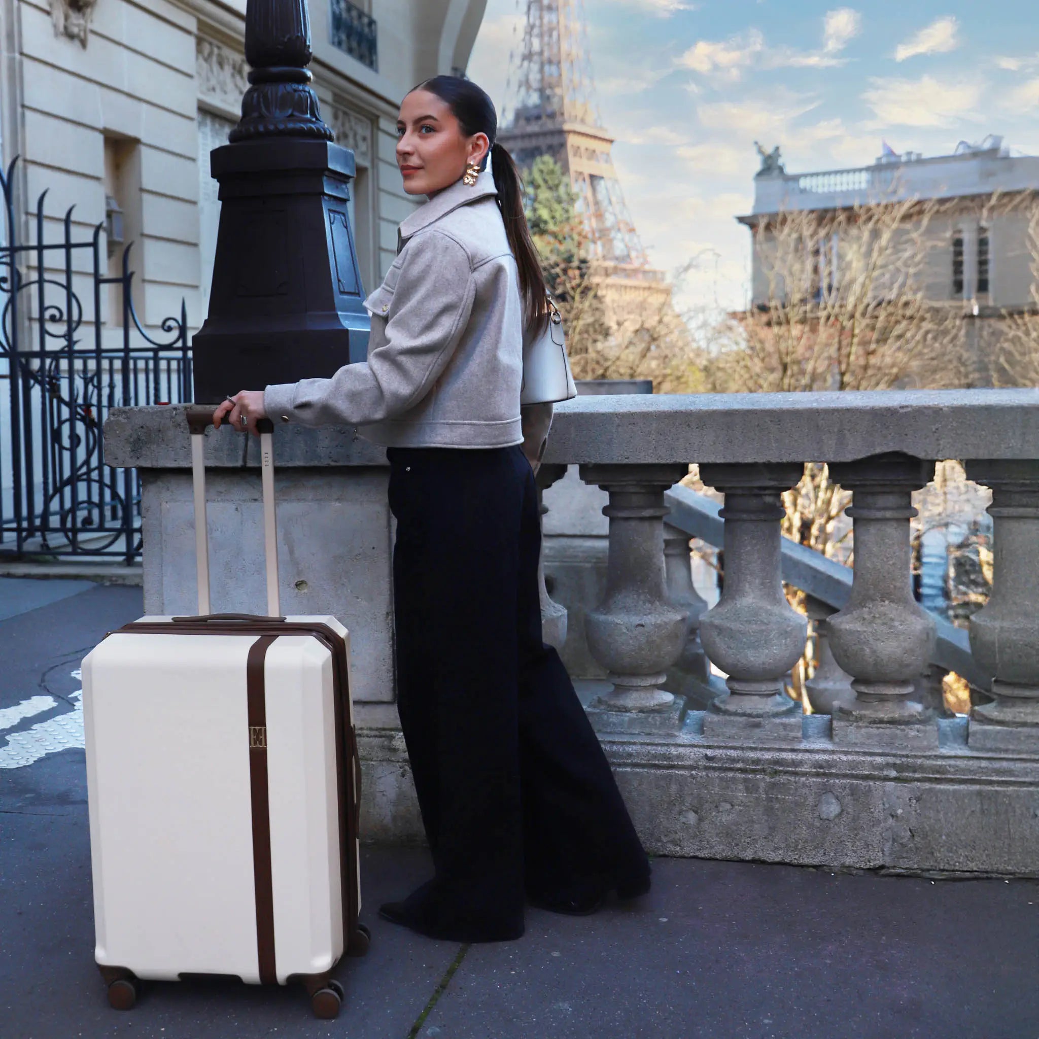 Woman with a suitcase standing in front of the Eiffel Tower
