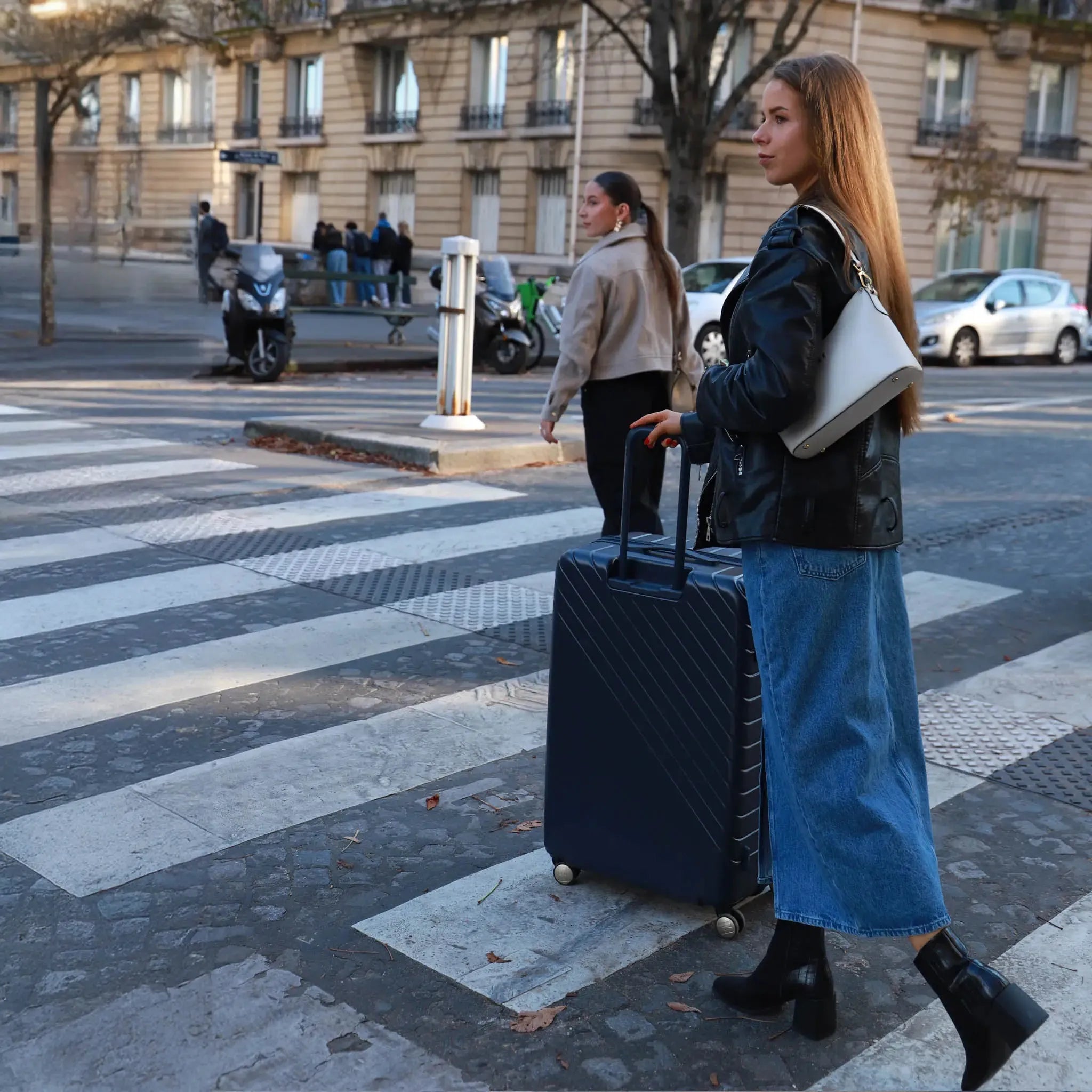 Woman with a suitcase crossing a street in an urban setting