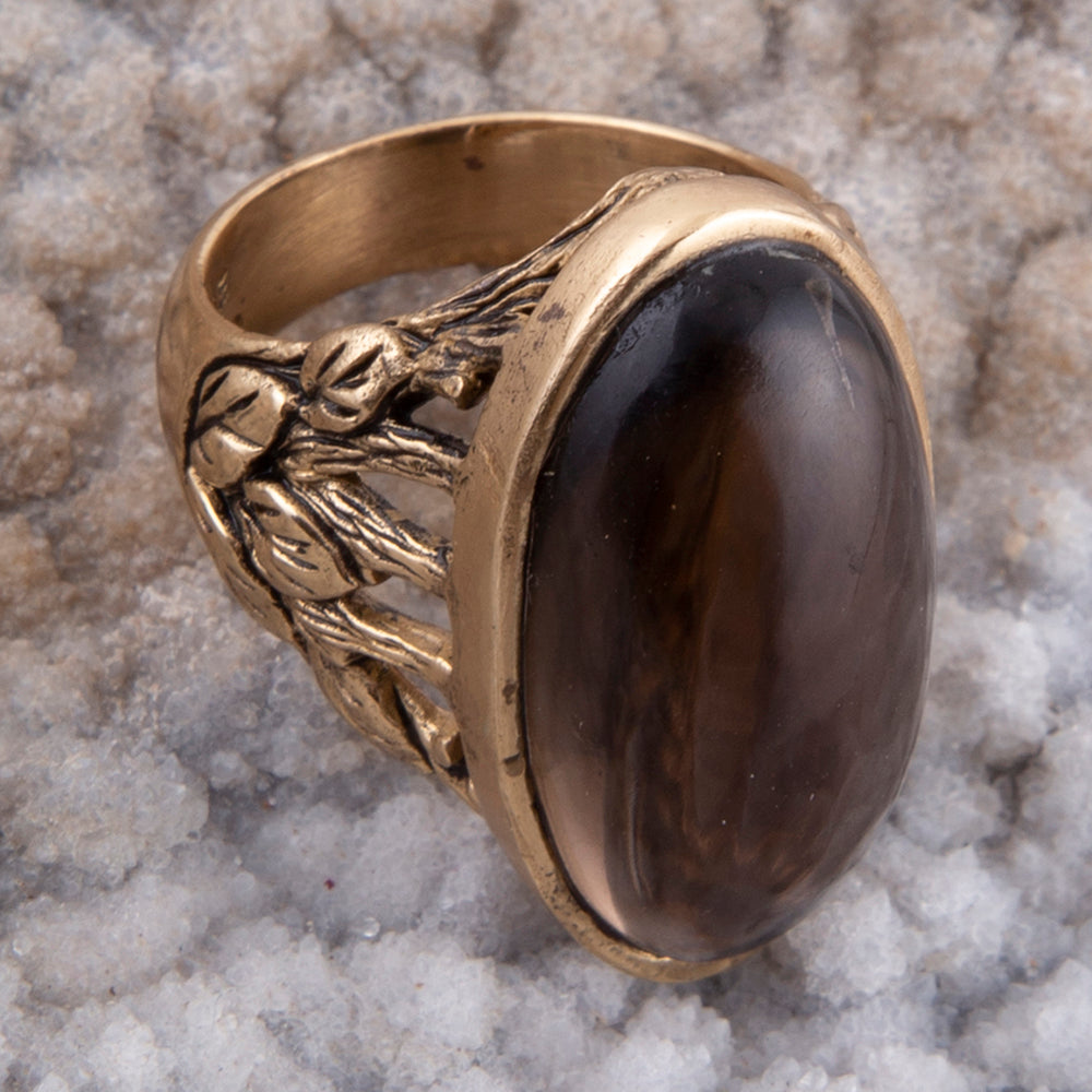 Gold ring with a dark stone on a textured gray background