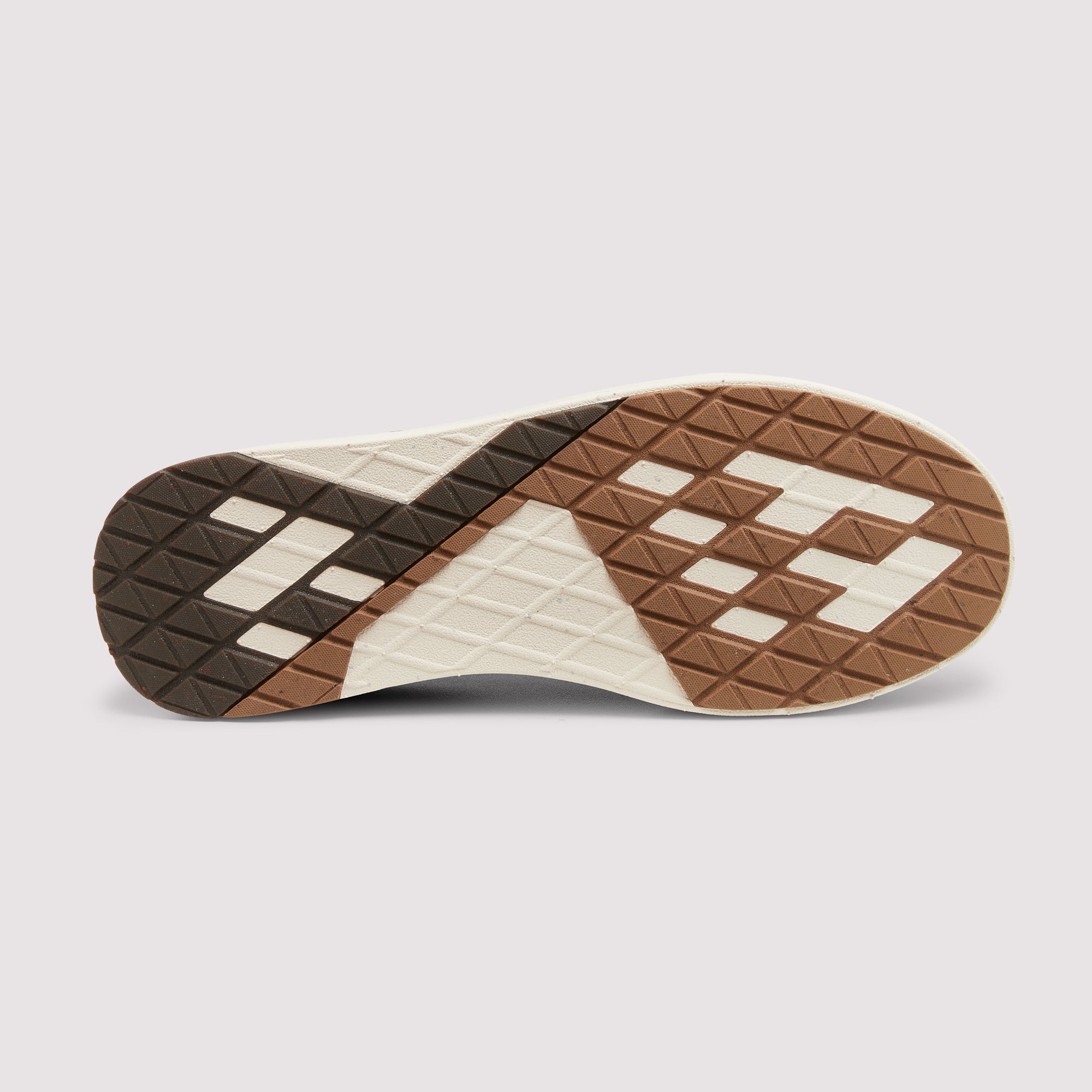 The outsole of a sneaker shown from a top-down view, featuring a geometric pattern in brown, dark brown, and off-white with a diamond tread design.