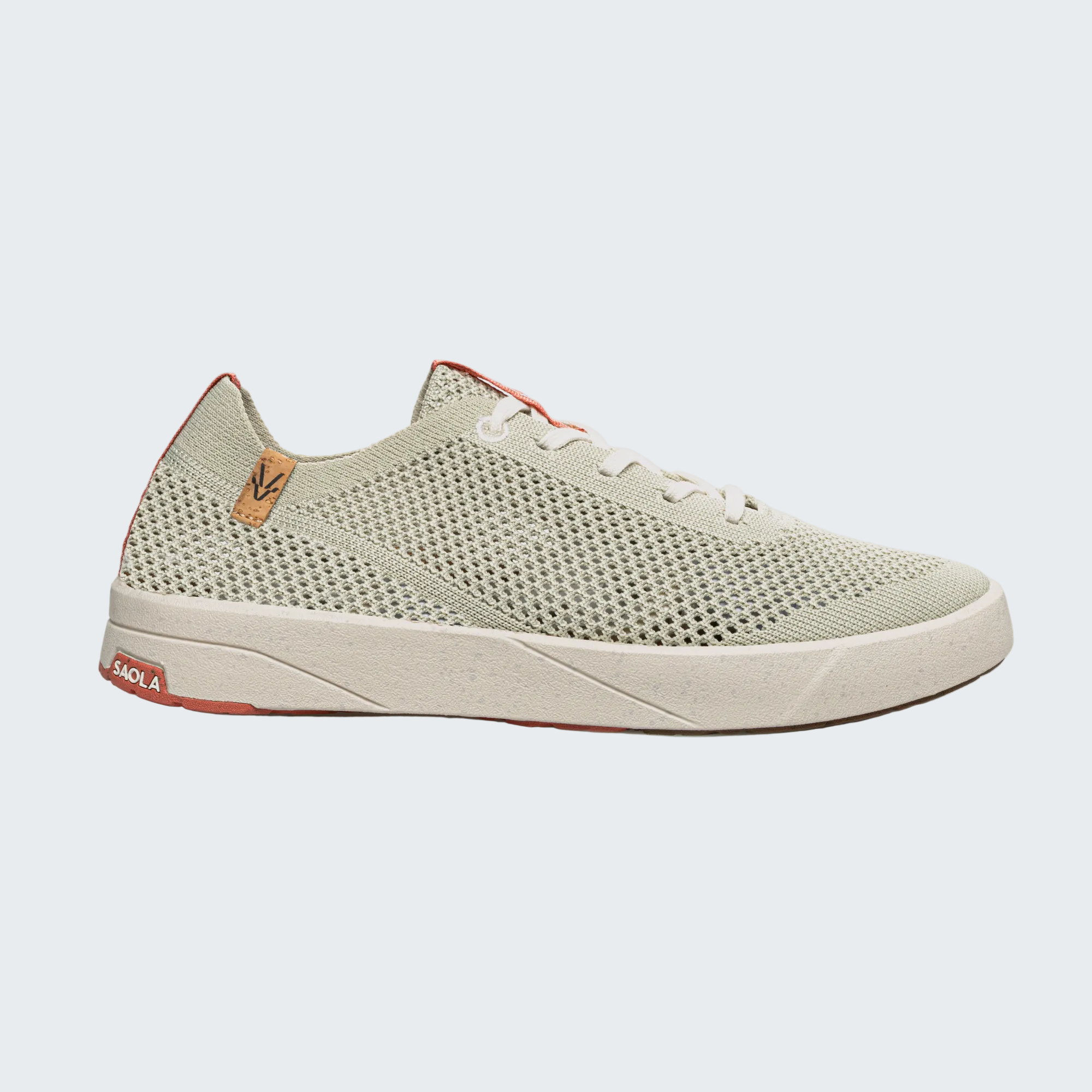 A single low-top sneaker shown in a side profile on a light gray background. The shoe features a light sage green mesh upper, white laces, a thick off-white midsole, and subtle coral-red accents on the heel and outsole.
