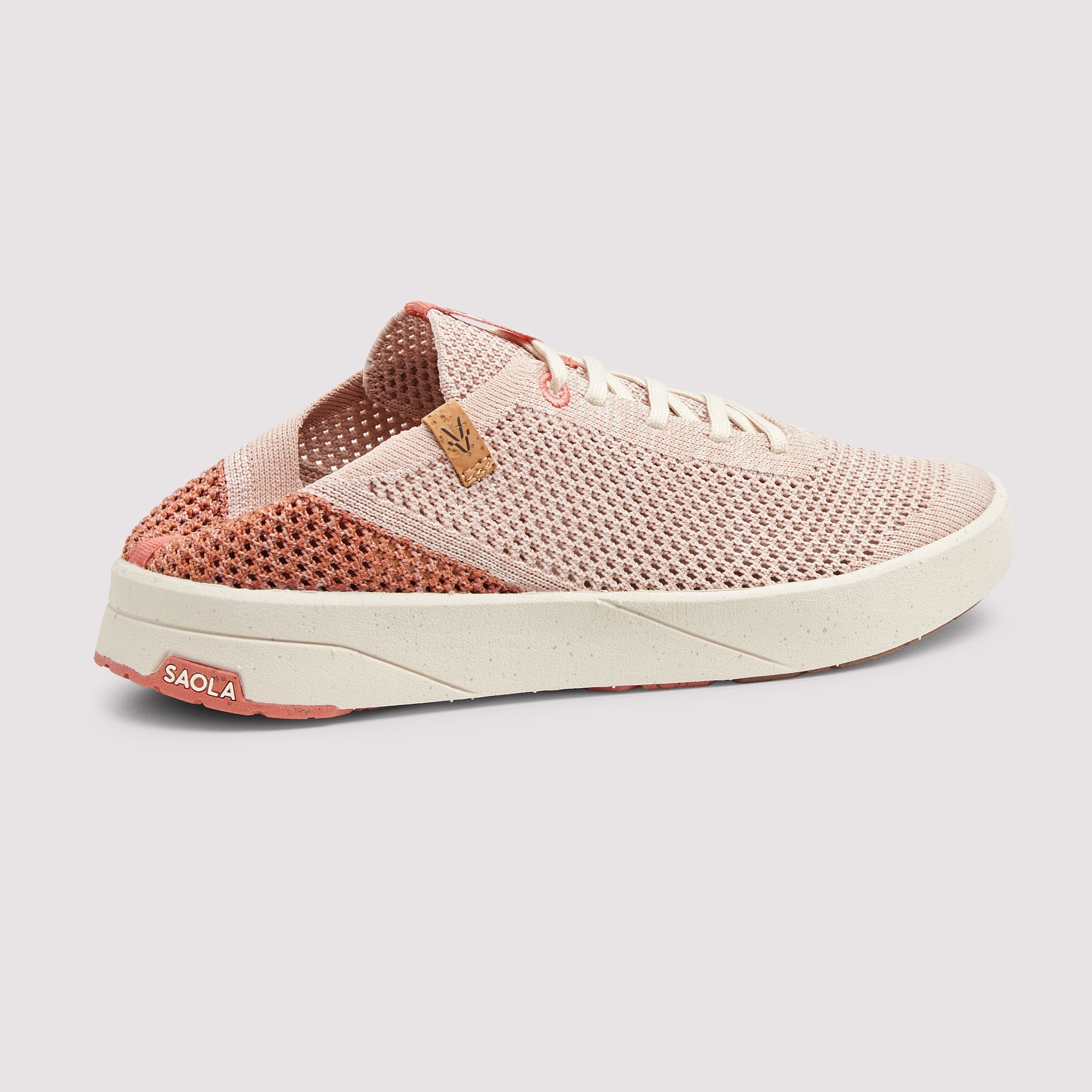 A single women's slip-on sneaker by Saola, featuring a light pink mesh upper, a coral-pink knit collar, a thick off-white sole, and a small tan leather logo tab on the side.