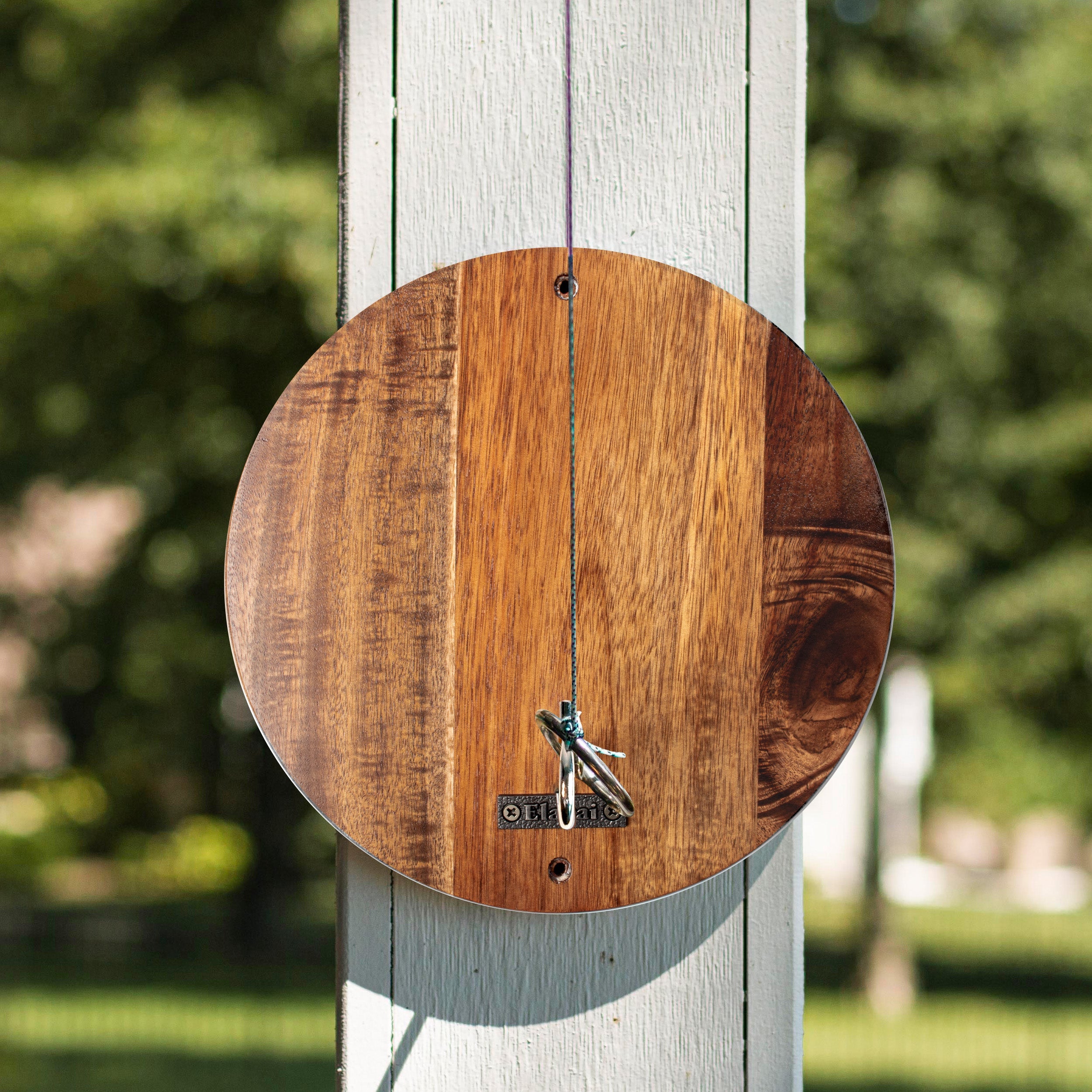Wooden clock on a white post with a blurred green background