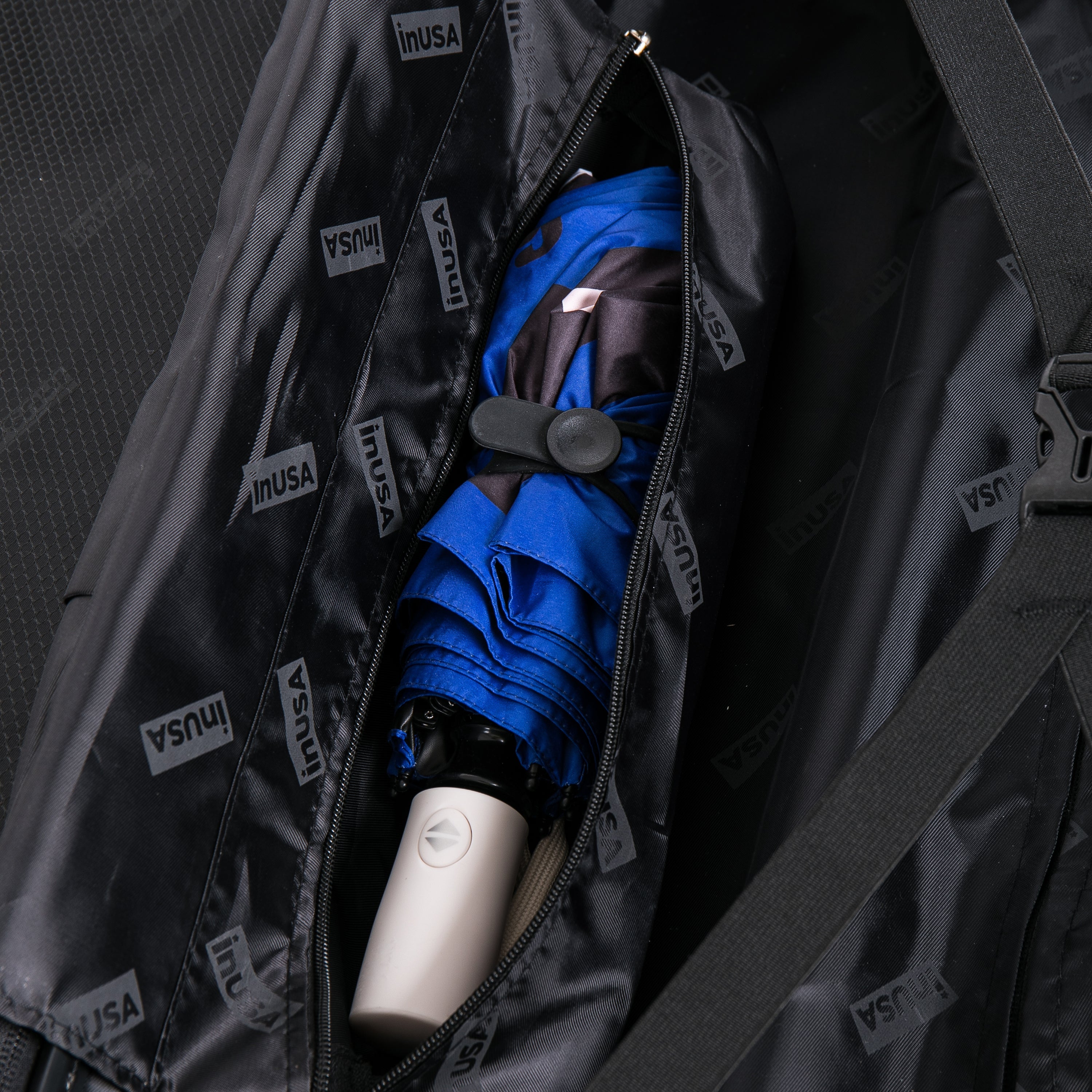 Blue umbrella inside a black raincoat with INUSA branding.