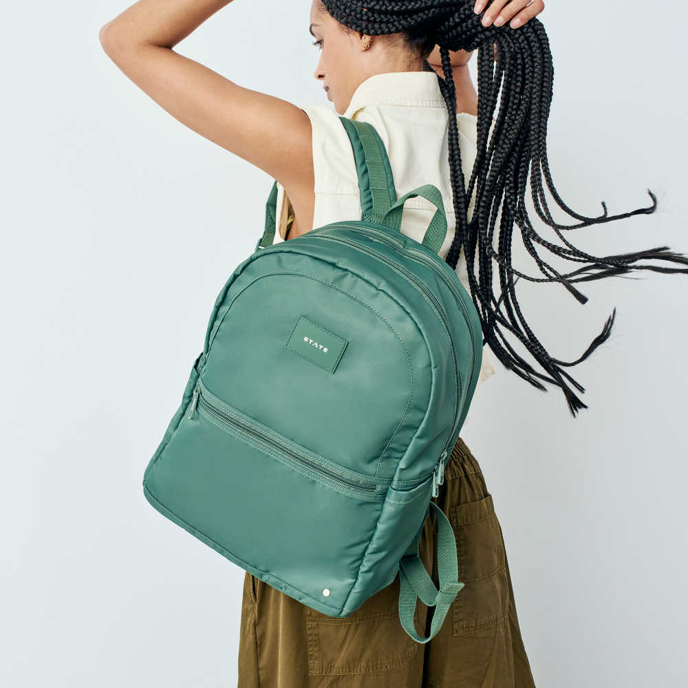 Person wearing a green backpack with a plain background