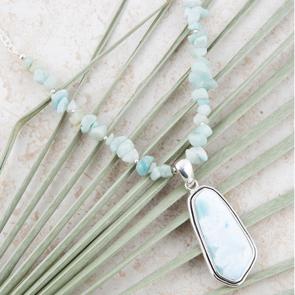 Necklace with light blue beads and a silver pendant on a natural background