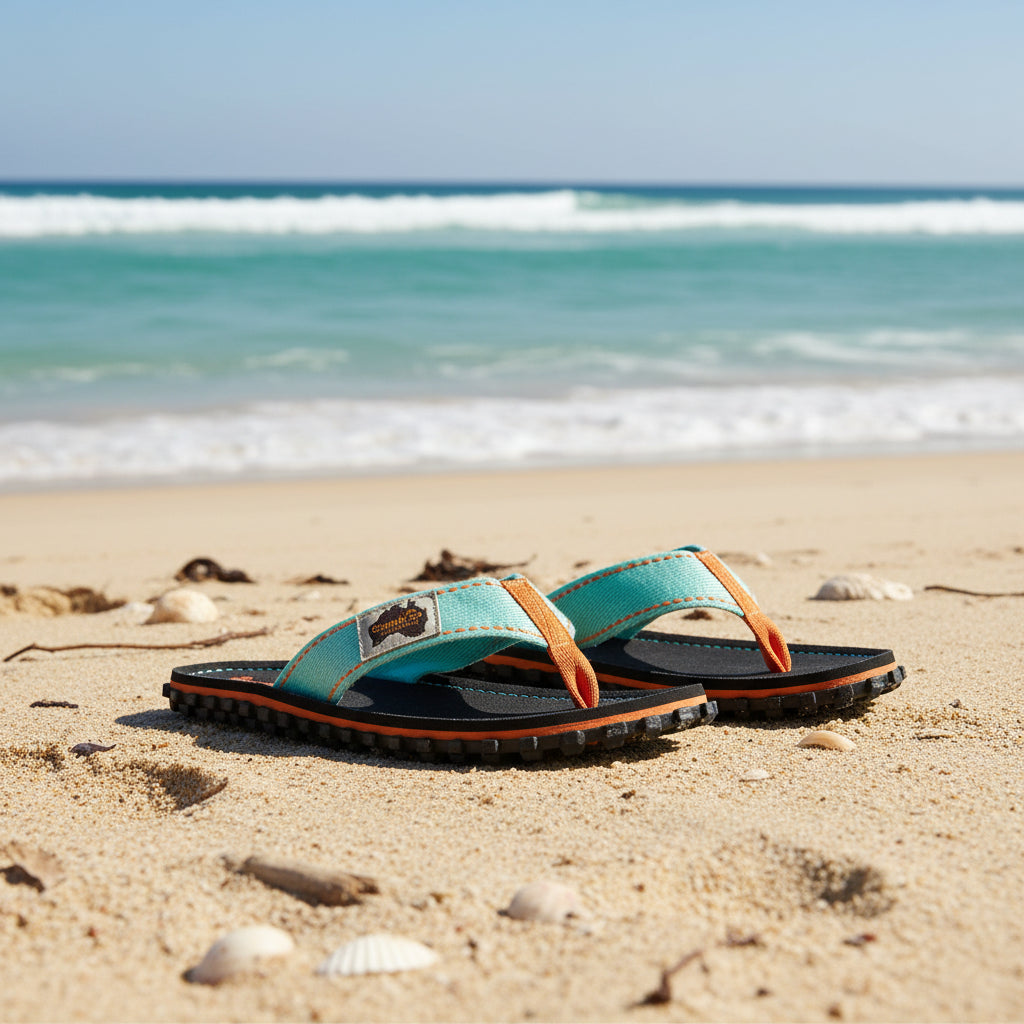 Pair of black sandals with orange and light blue straps on a white background