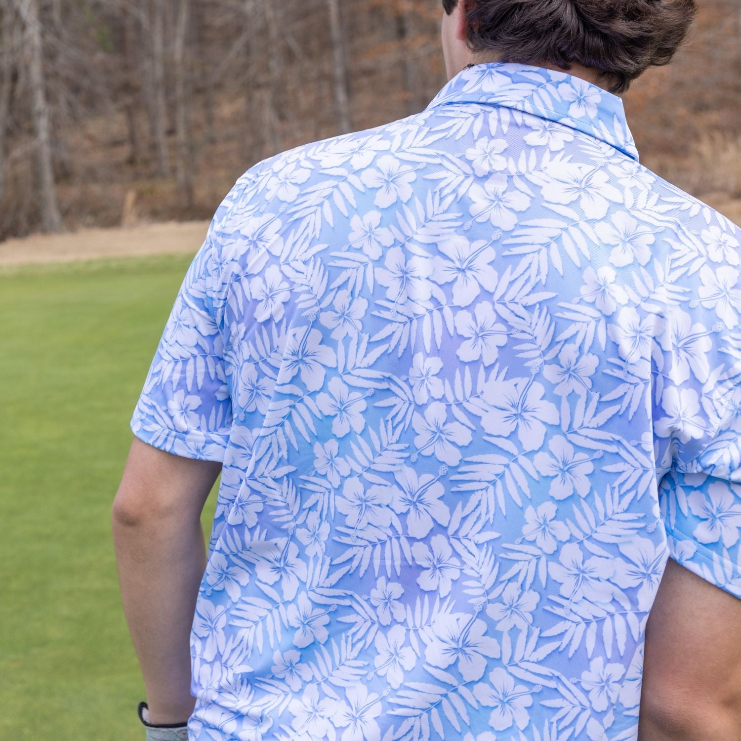 Person wearing a blue floral shirt outdoors on a grassy area