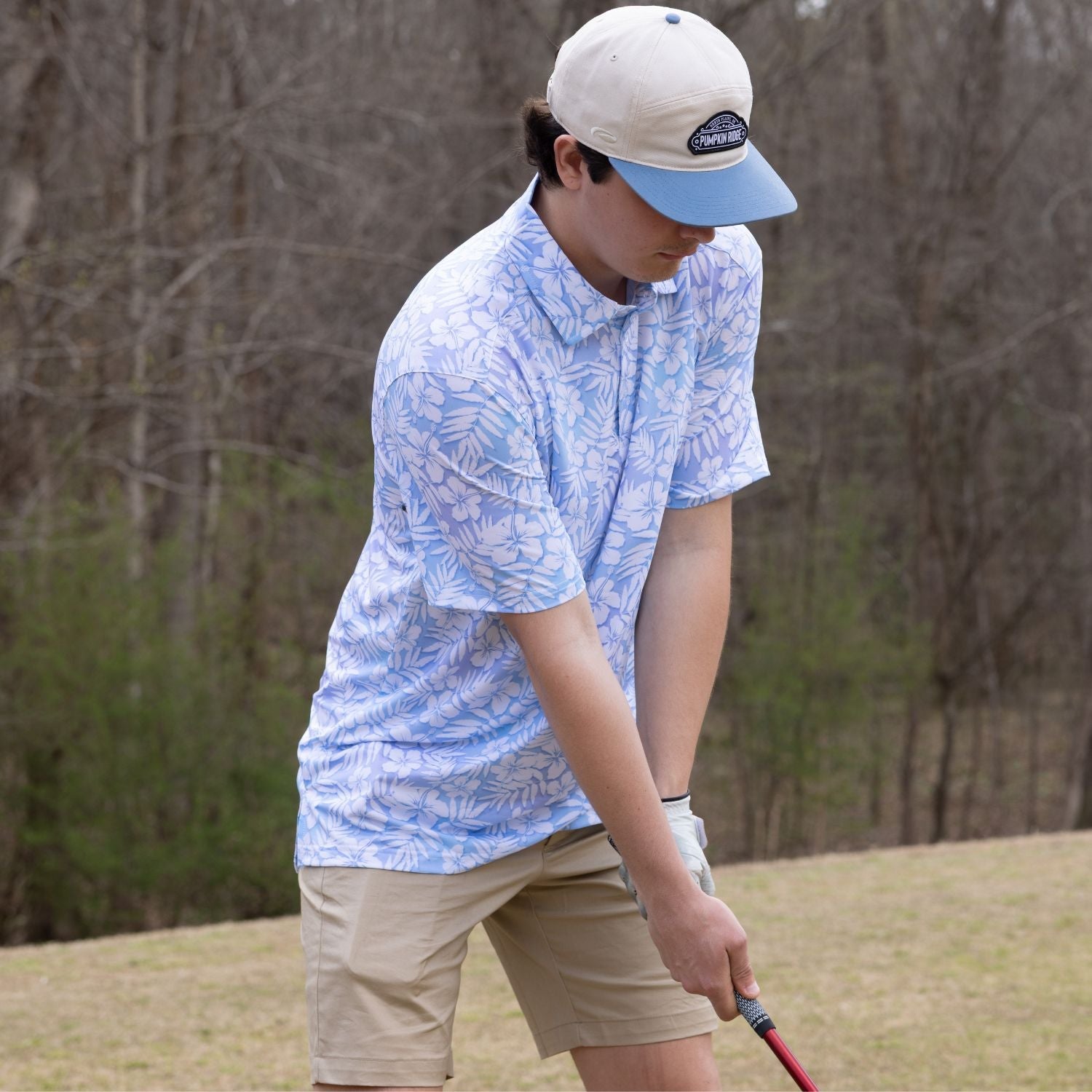Person playing golf on a course with trees in the background