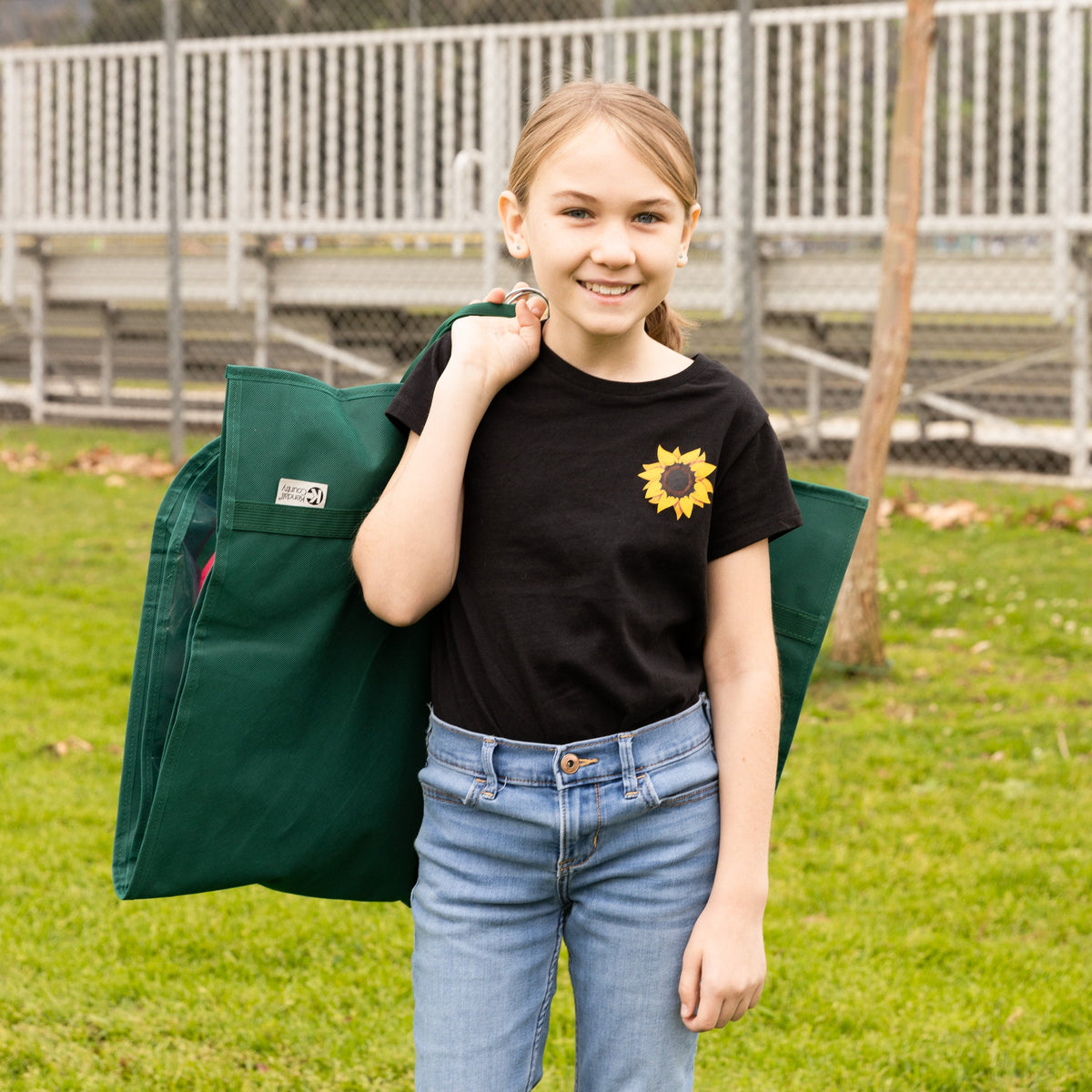 Person holding a green bag with a sunflower design on a grassy area