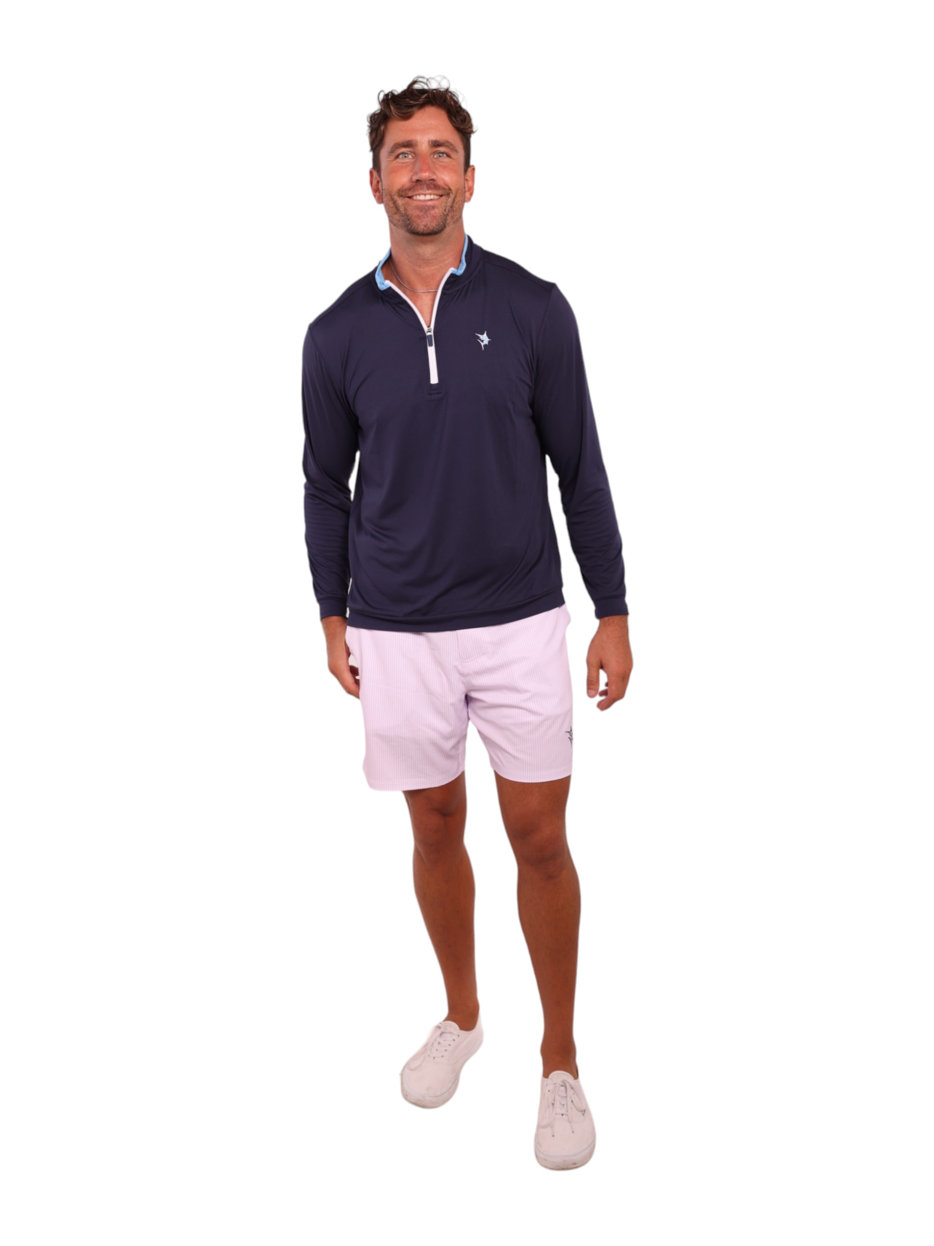 Man wearing a navy long-sleeve shirt with a zipper and light pink shorts on a white background