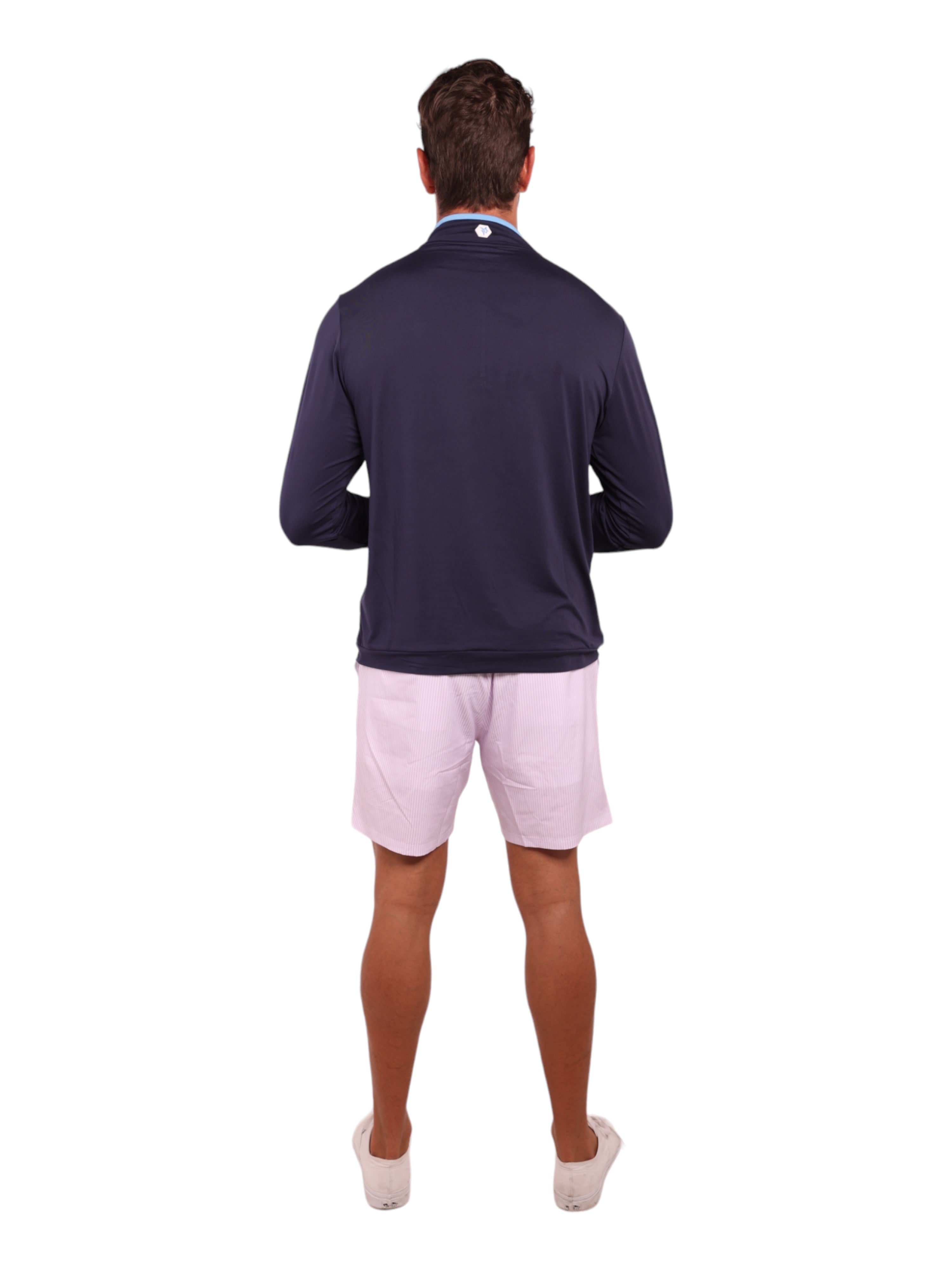 Man wearing a navy long-sleeve shirt and light pink shorts on a white background