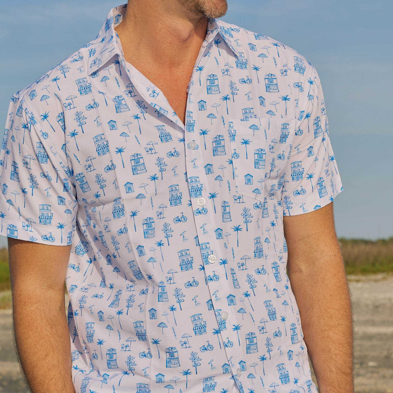 Person wearing a white shirt with blue patterns against a blurred natural background