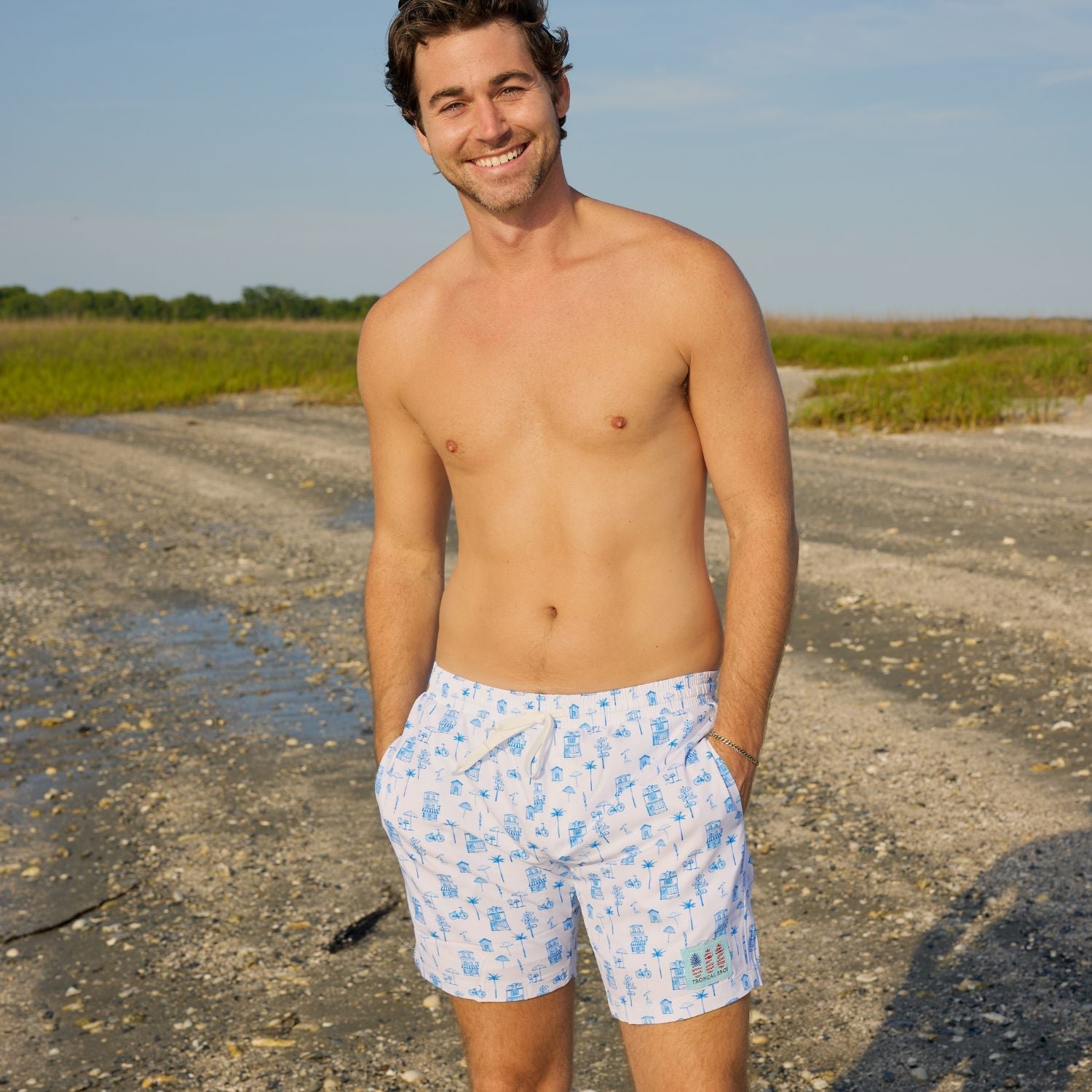 Man wearing blue patterned shorts standing on a beach