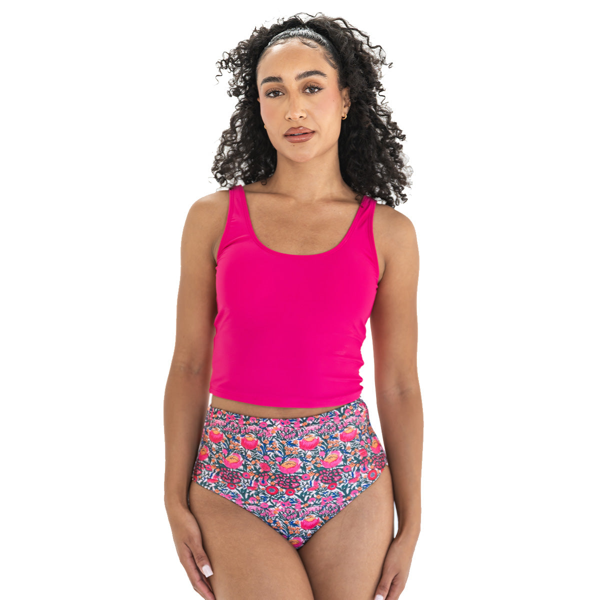 Woman wearing a bright pink tank top and floral high-waisted bikini bottoms on a white background
