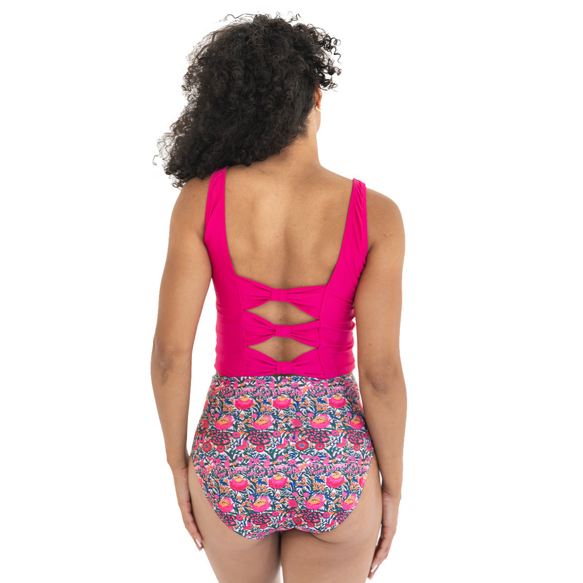 Woman wearing a pink tank top and floral shorts on a white background