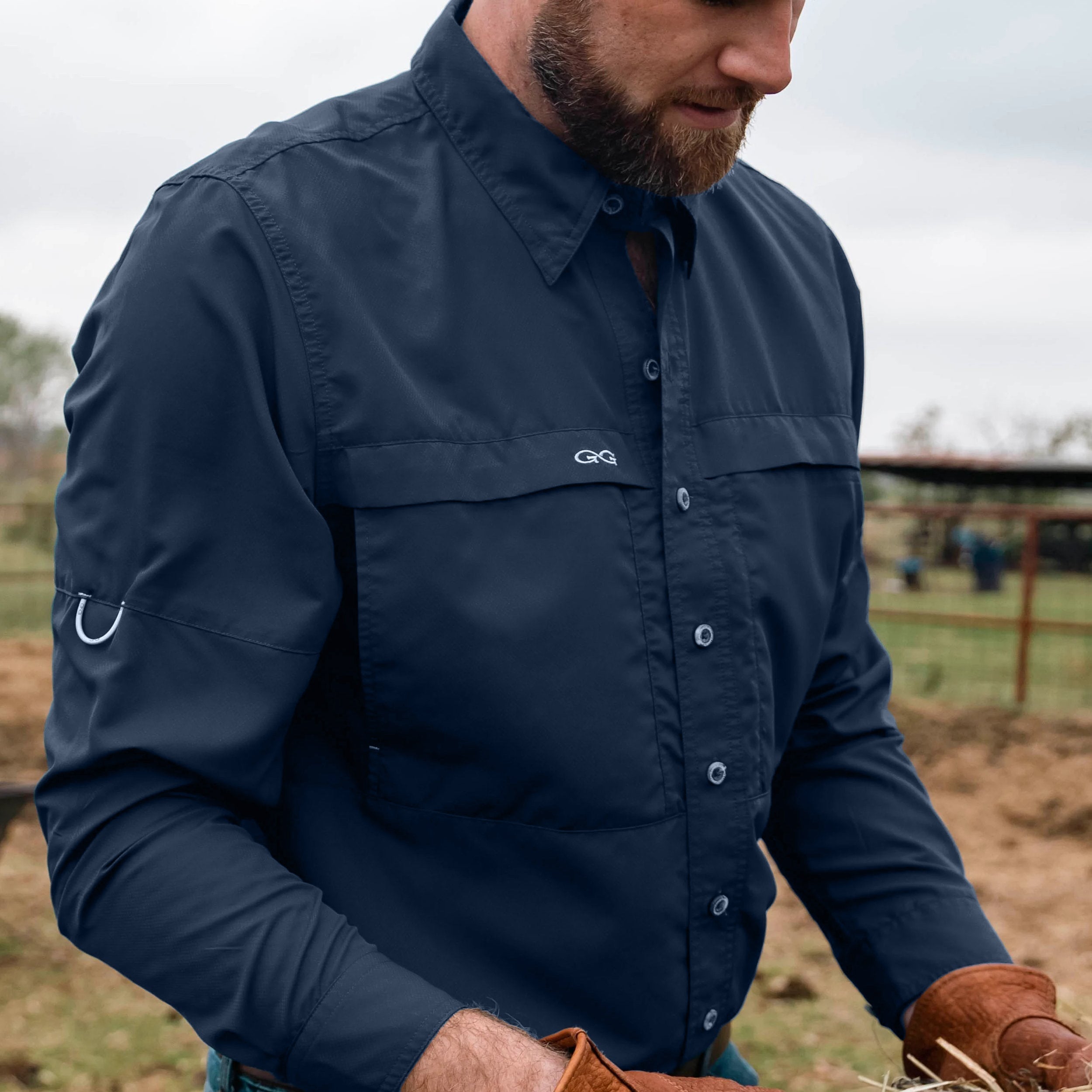 Man wearing a navy blue shirt with a logo, standing outdoors.