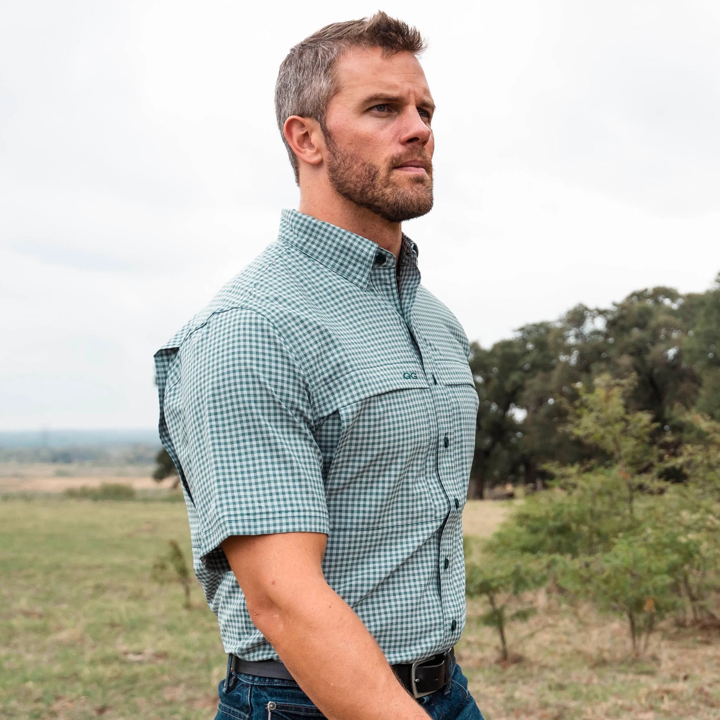 Man wearing a green checkered shirt in an outdoor setting