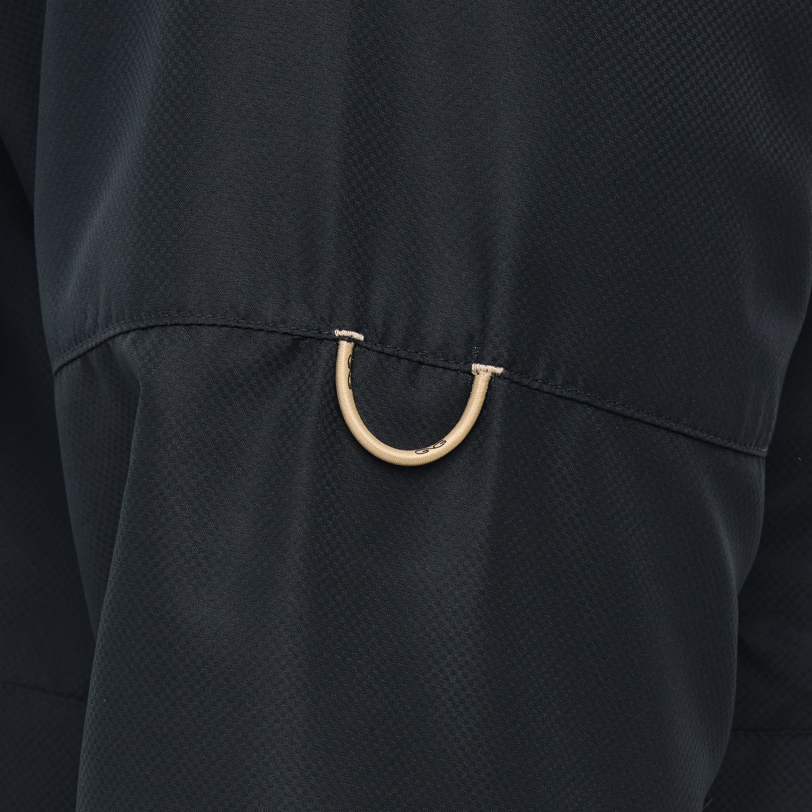 Close-up of a black textured fabric with a gold metal ring detail.