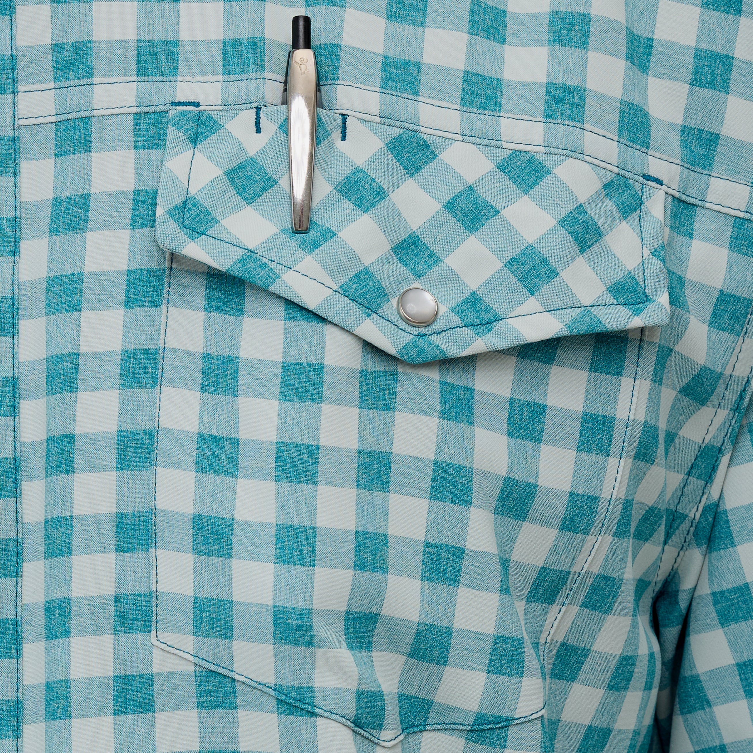 Close-up of a blue and white checkered shirt with a pen in the pocket.