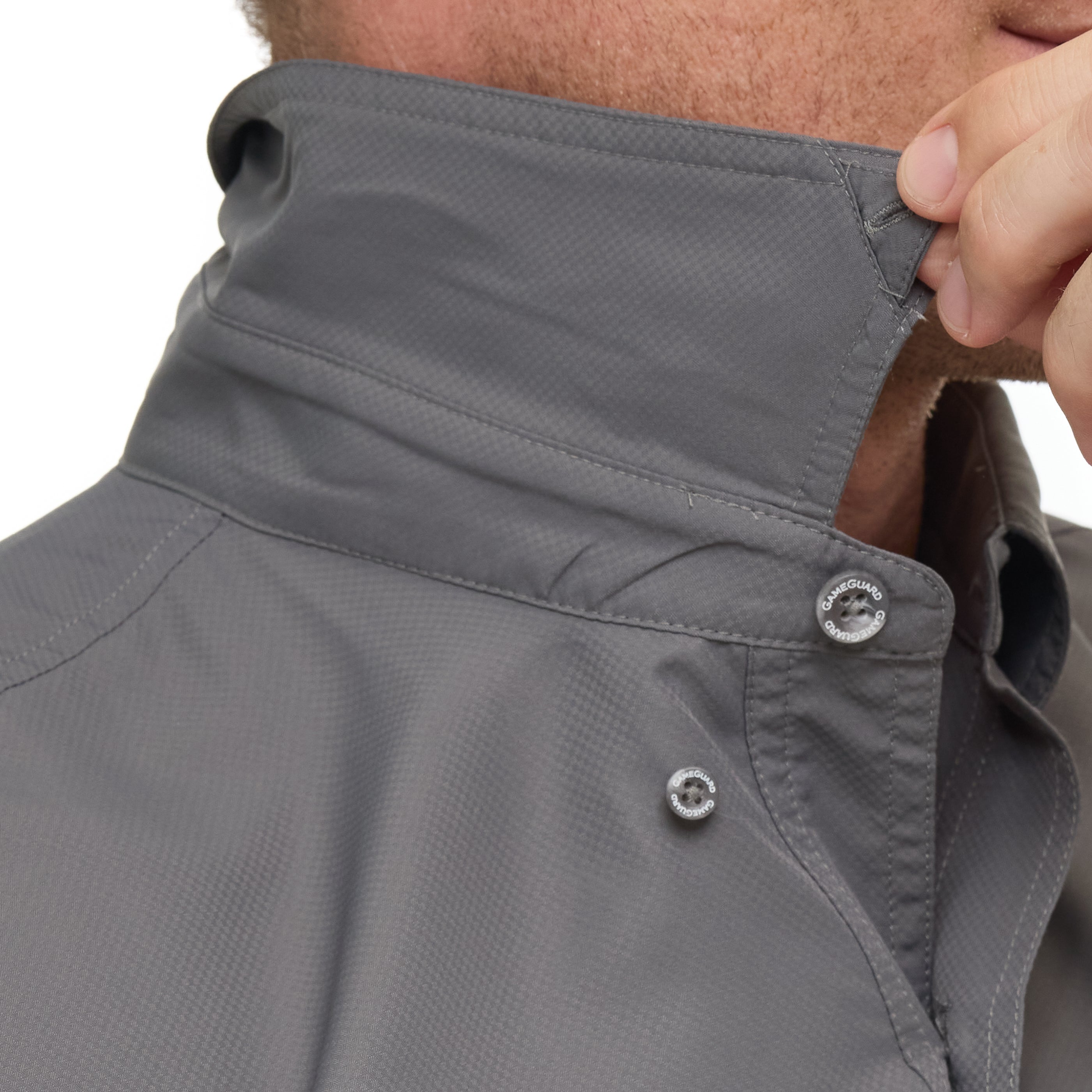 Close-up of a person adjusting the collar of a gray jacket with buttons.
