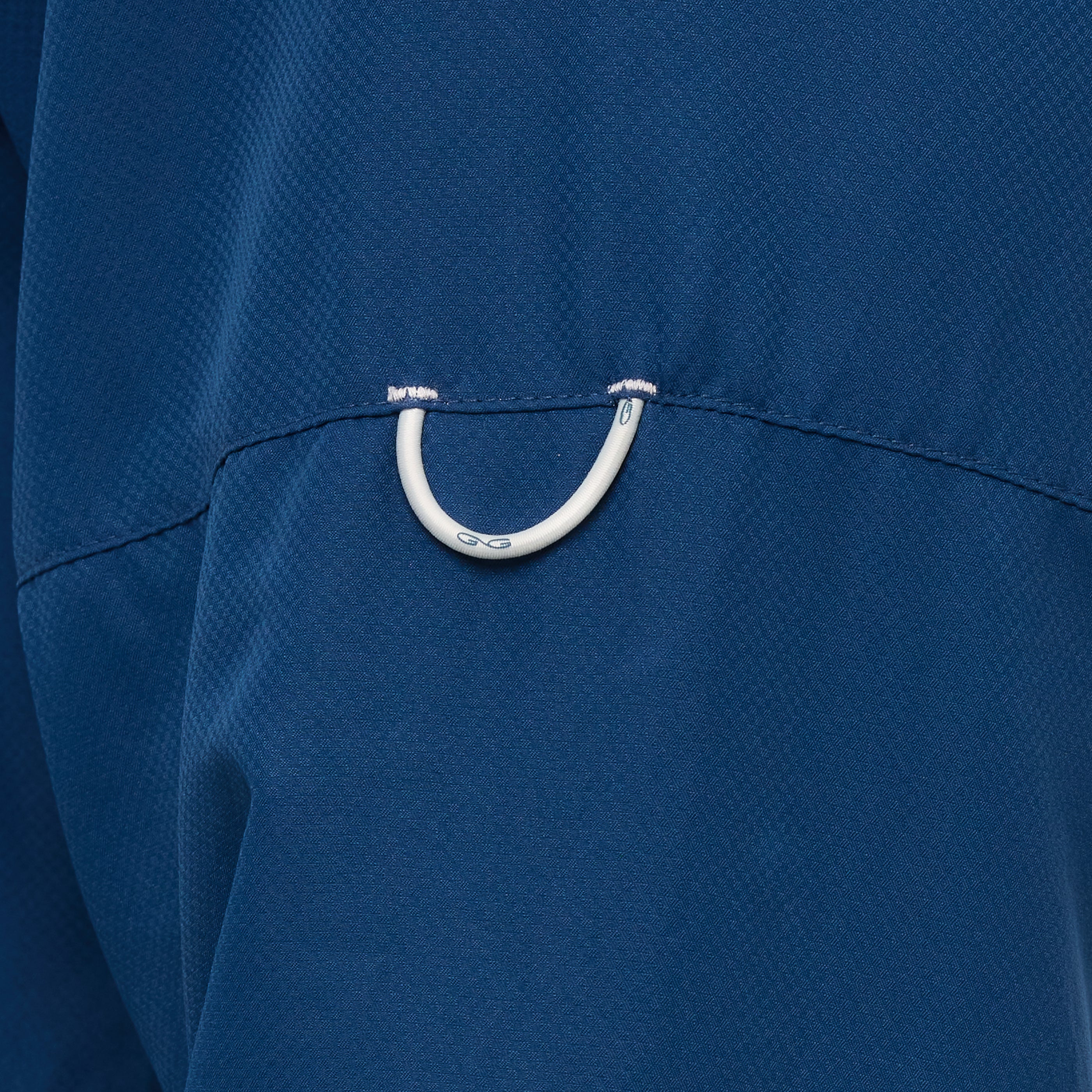 Close-up of a blue garment with a white metal ring on a blue background