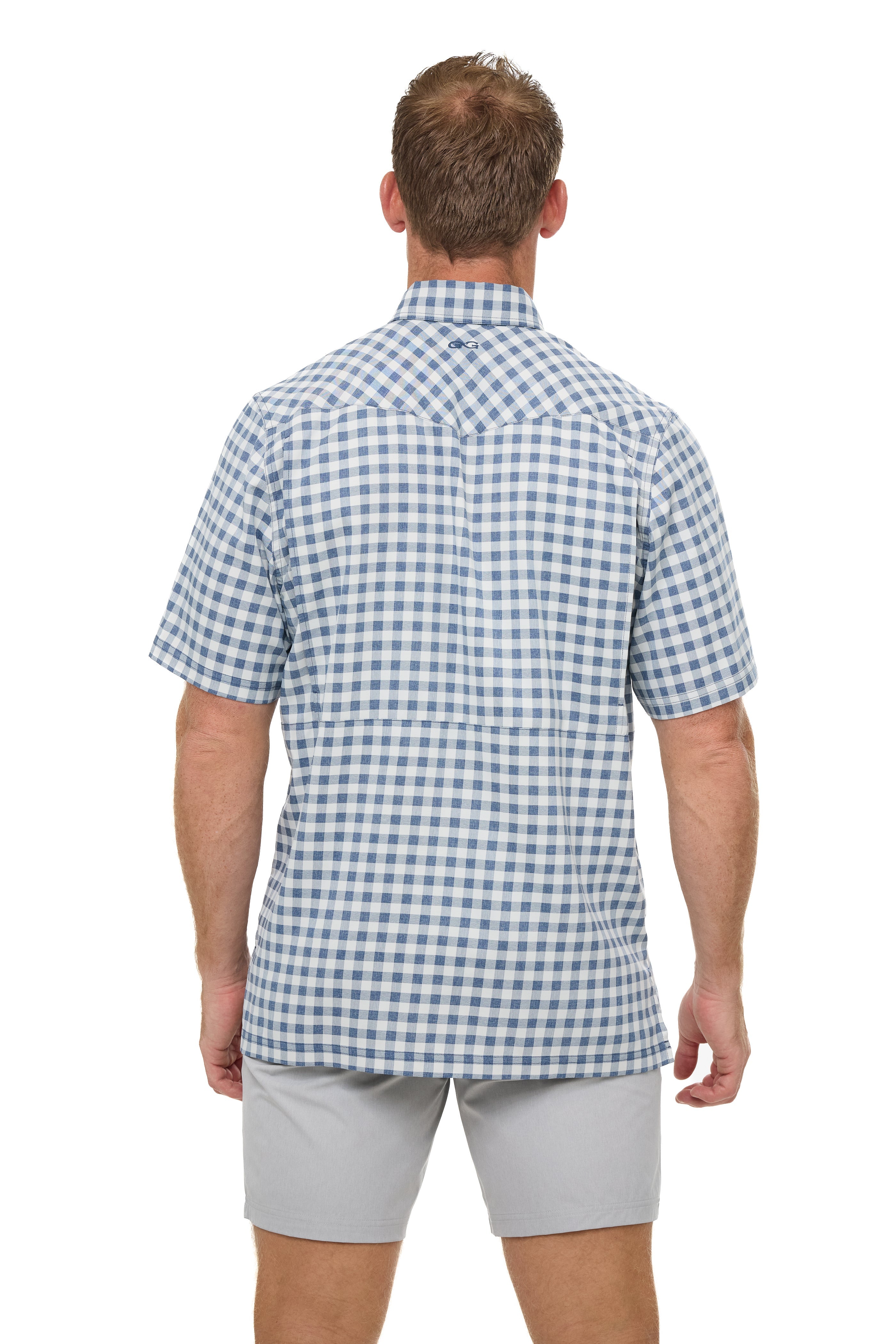 Man wearing a blue and white checkered shirt and light gray shorts on a white background