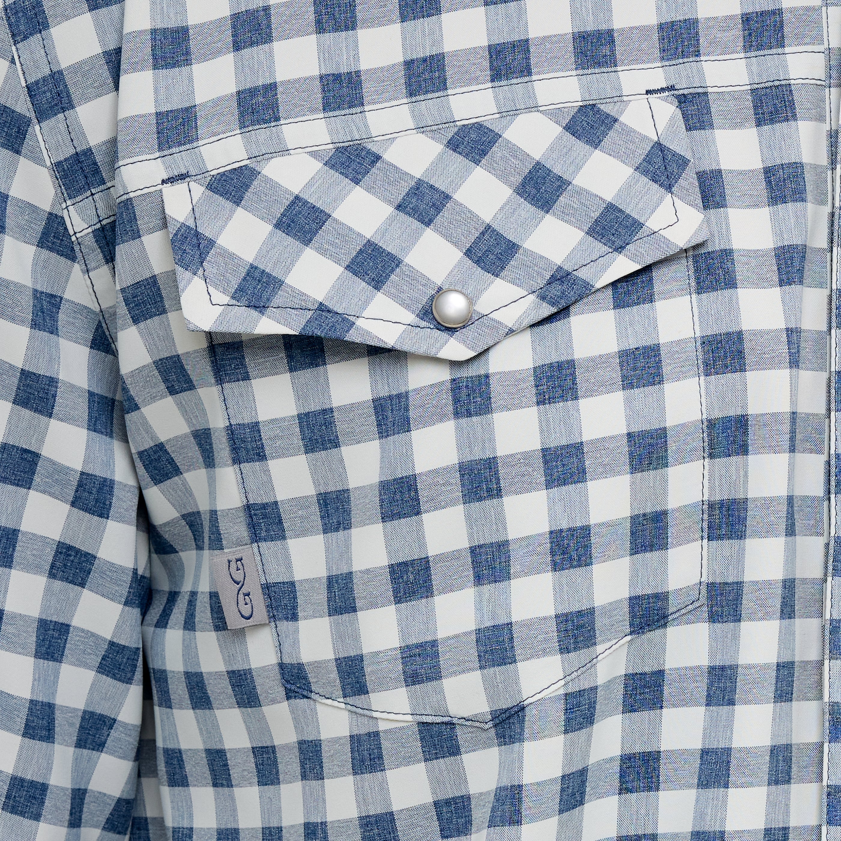 Close-up of a blue and white checkered shirt with a button.