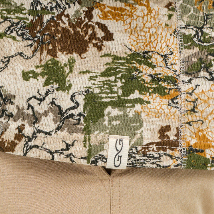 Close-up of a camouflage-patterned fabric with a brand label on a beige background