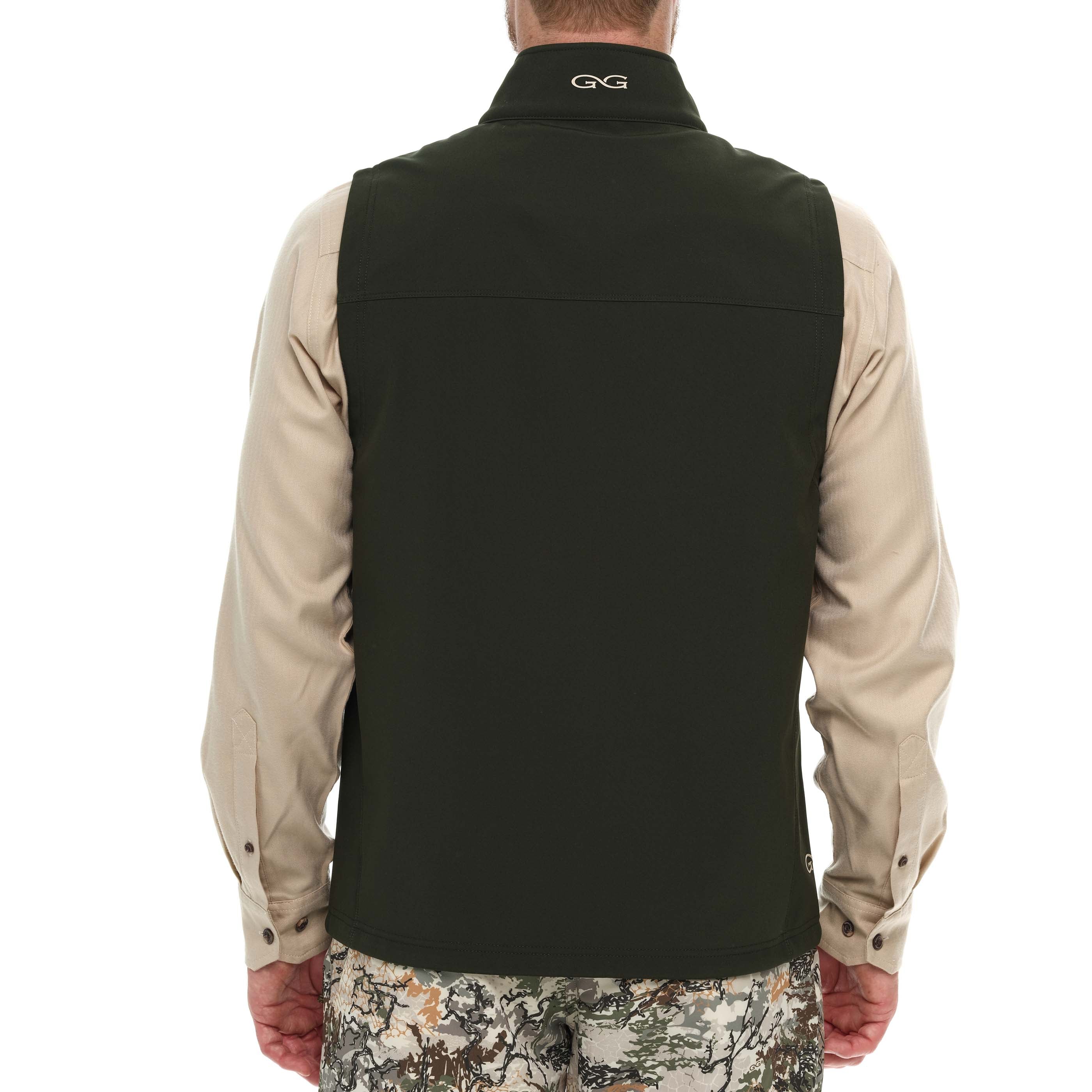 Person wearing a black vest over a beige shirt with a white background